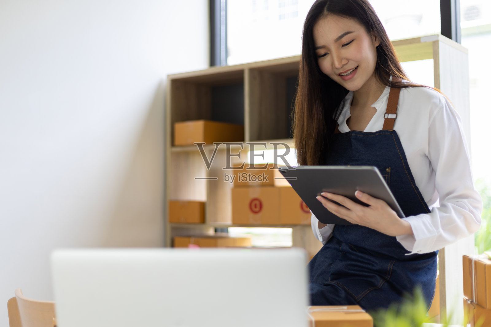 创办小企业中小企业的企业主是女性企业家，她们工作在网上做收货箱和检查，准备把箱子包装好，卖给客户，在网上经营中小企业。照片摄影图片