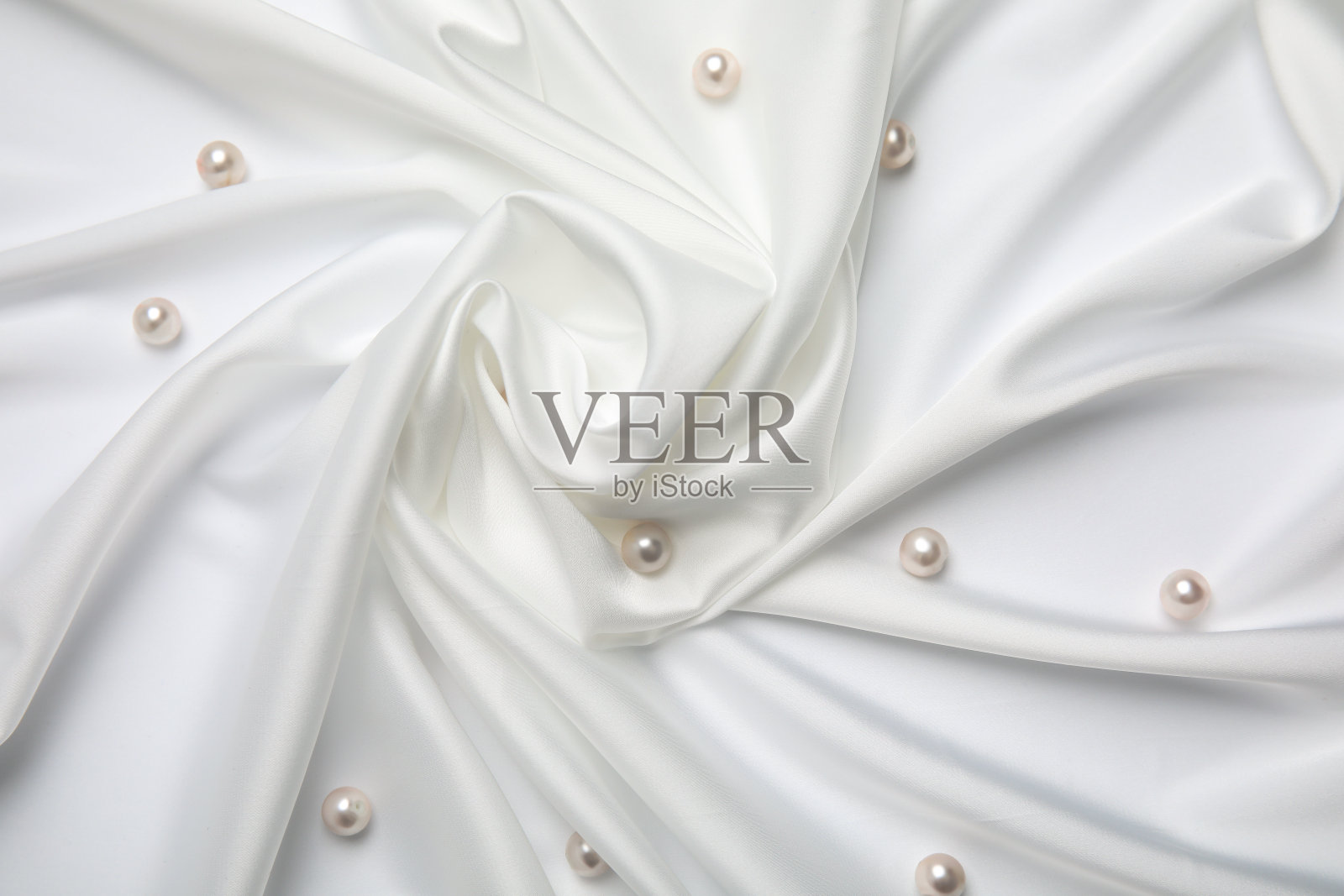 美丽的珍珠镶嵌在白色丝绸上，平铺着照片摄影图片