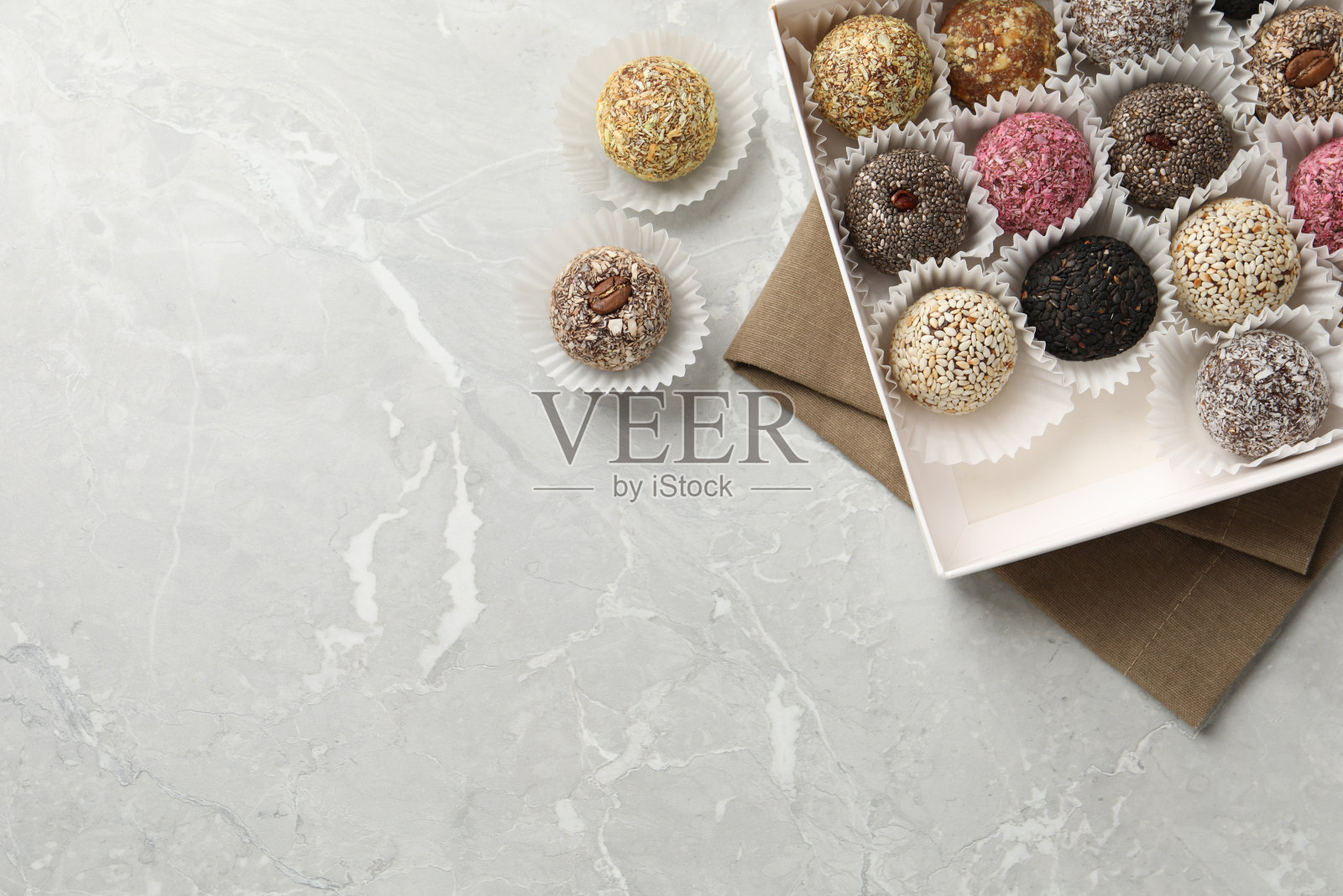 不同美味的素食糖果球在浅灰色大理石桌子上，平铺。空间的文本照片摄影图片