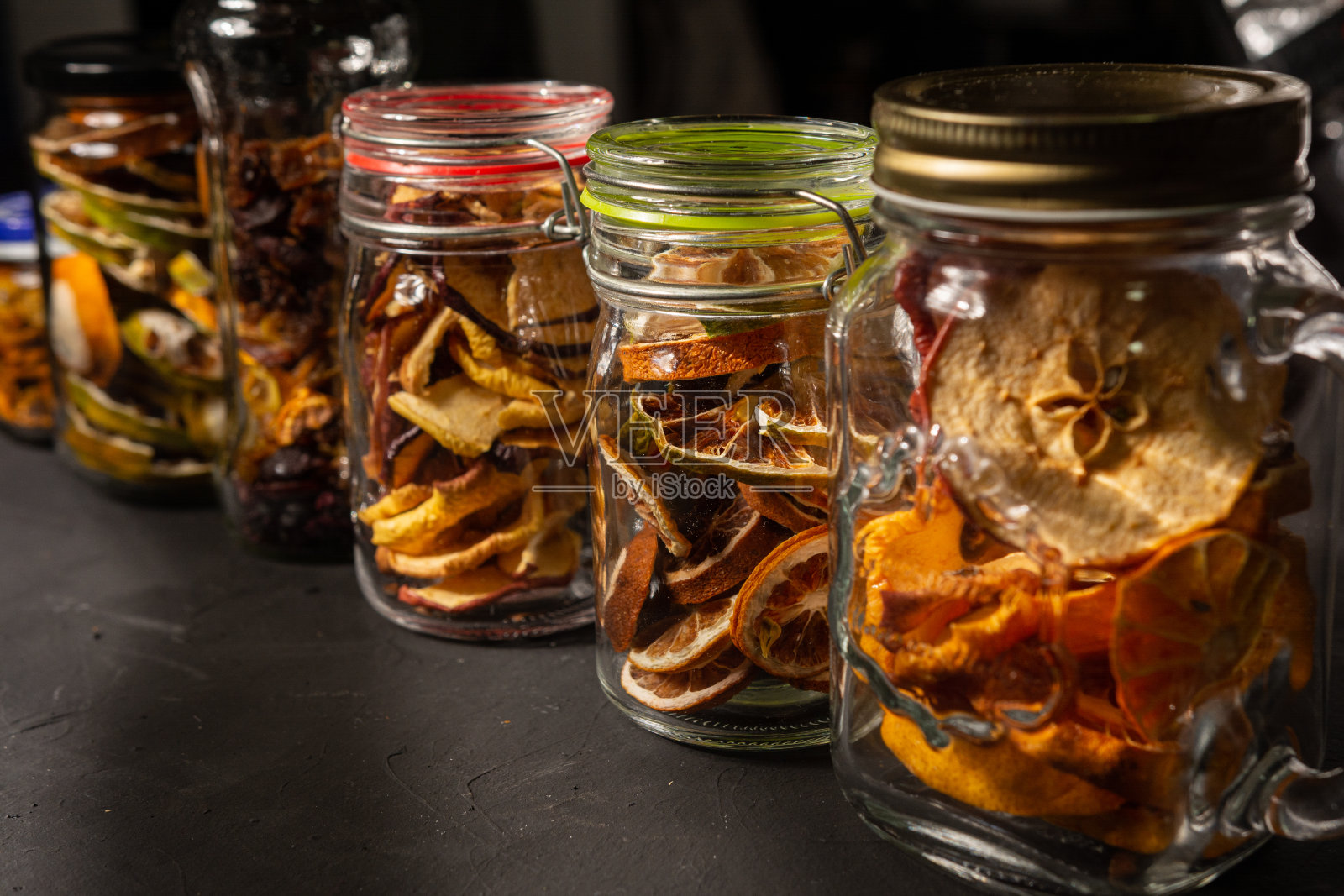 黑色背景的玻璃罐中有自制的脱水水果照片摄影图片