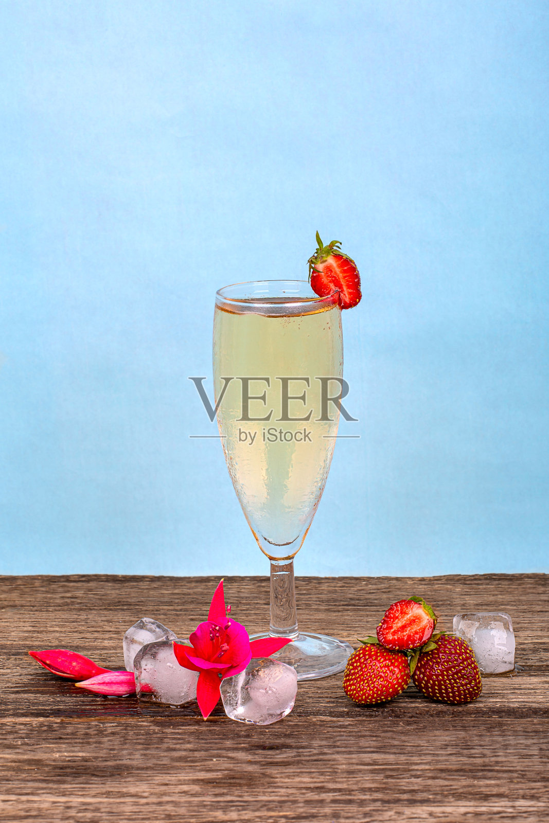 一杯薄雾香槟，新鲜草莓和冰块，蓝色的背景照片摄影图片