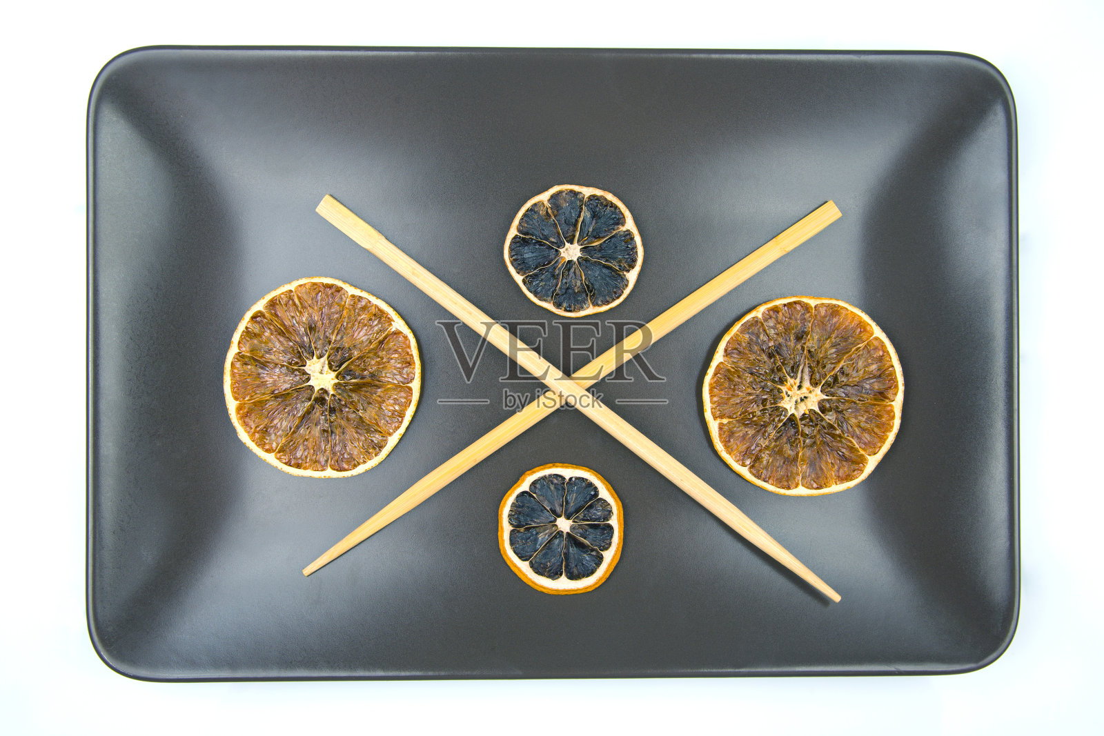 竹筷放在装有柑橘干的陶瓷盘子上。为食品照片摄影图片