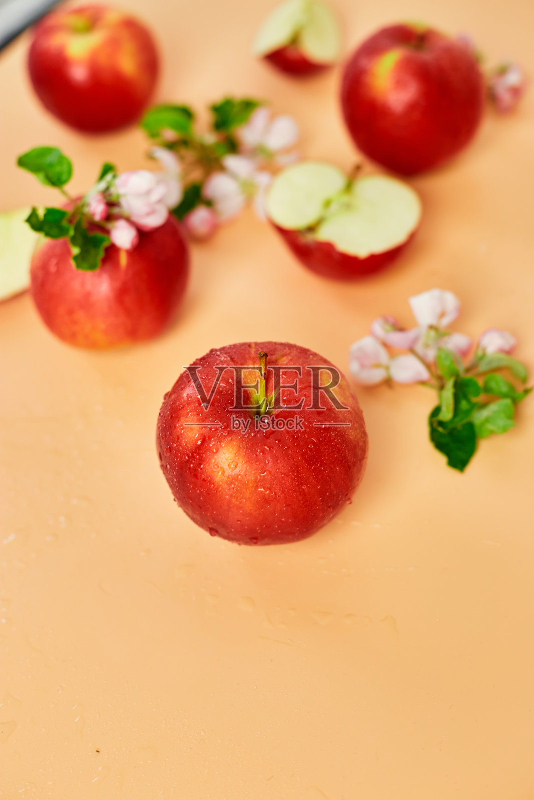 切片，整个红苹果和鲜花一个平面上的淡橙色背景，水果和鲜花，春天的概念。俯视图照片摄影图片