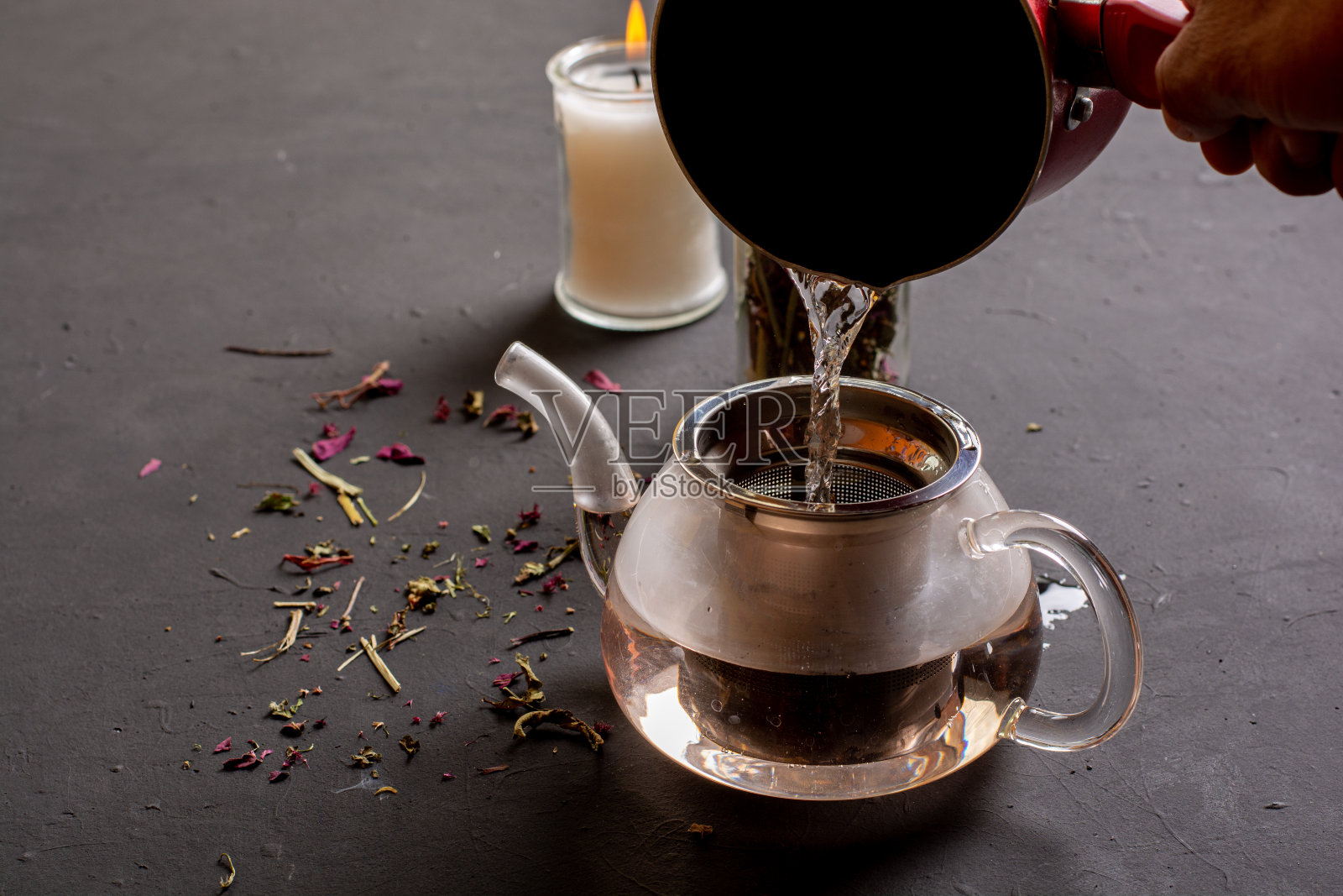 侧面的茶壶与茶添加热水在黑色的背景，茶的准备概念，以帮助放松照片摄影图片