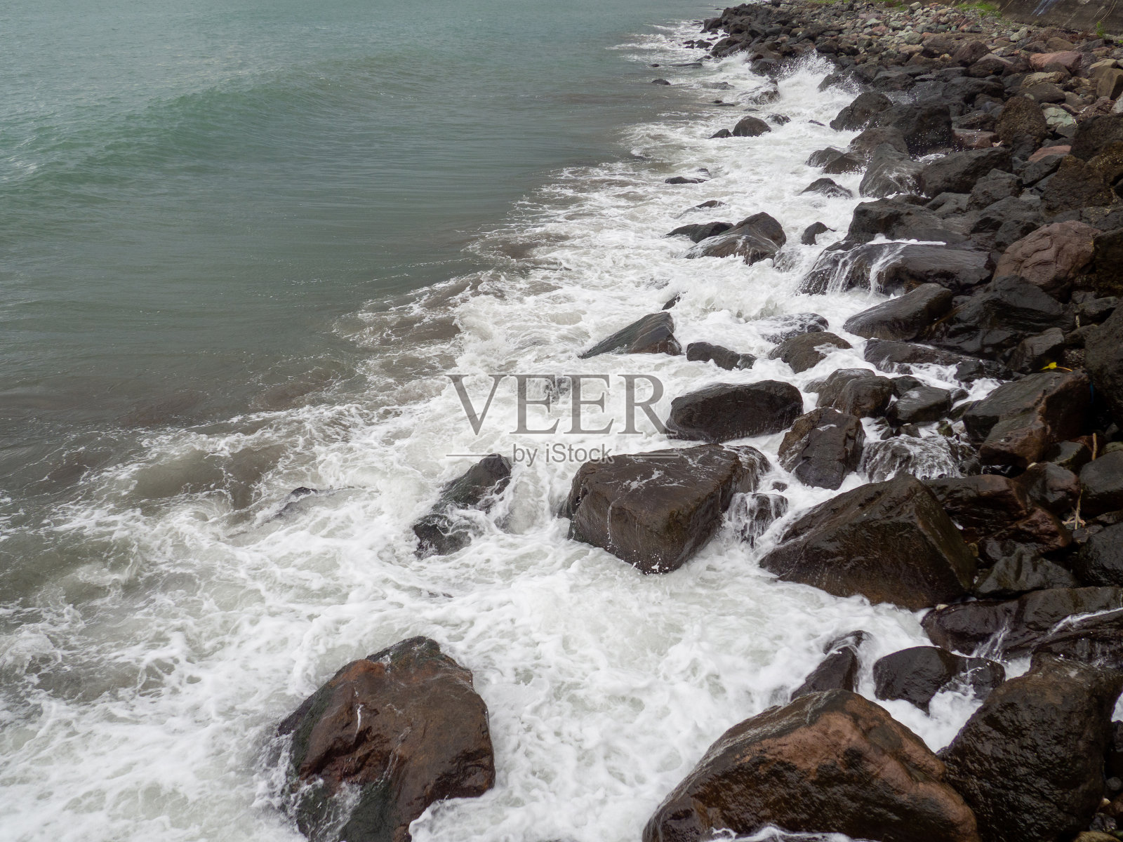 多岩石的海岸。海岸用巨石加固。码头上的大浪。前往土耳其。大波浪。照片摄影图片