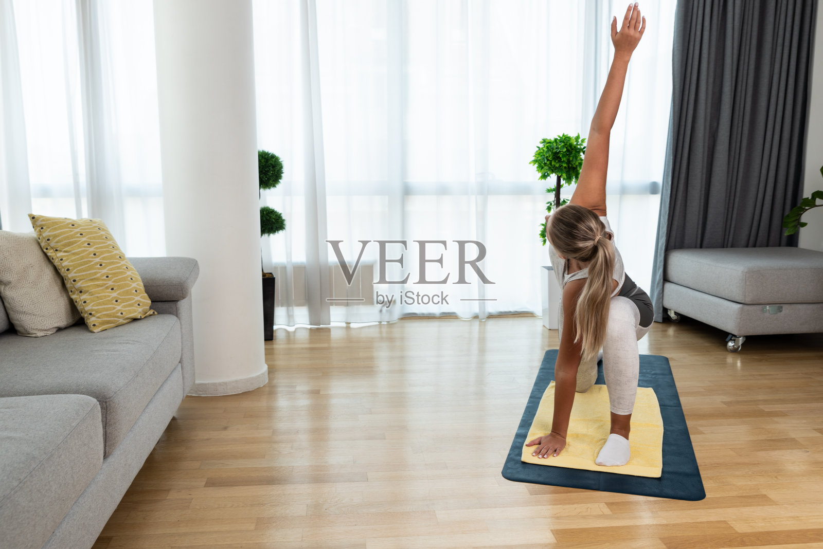 快乐迷人的年轻商业女性在积极运动穿坐在拉伸肌肉在她的公寓后或之前的工作，训练瑜伽班。在家锻炼可以缓解压力和疼痛。照片摄影图片