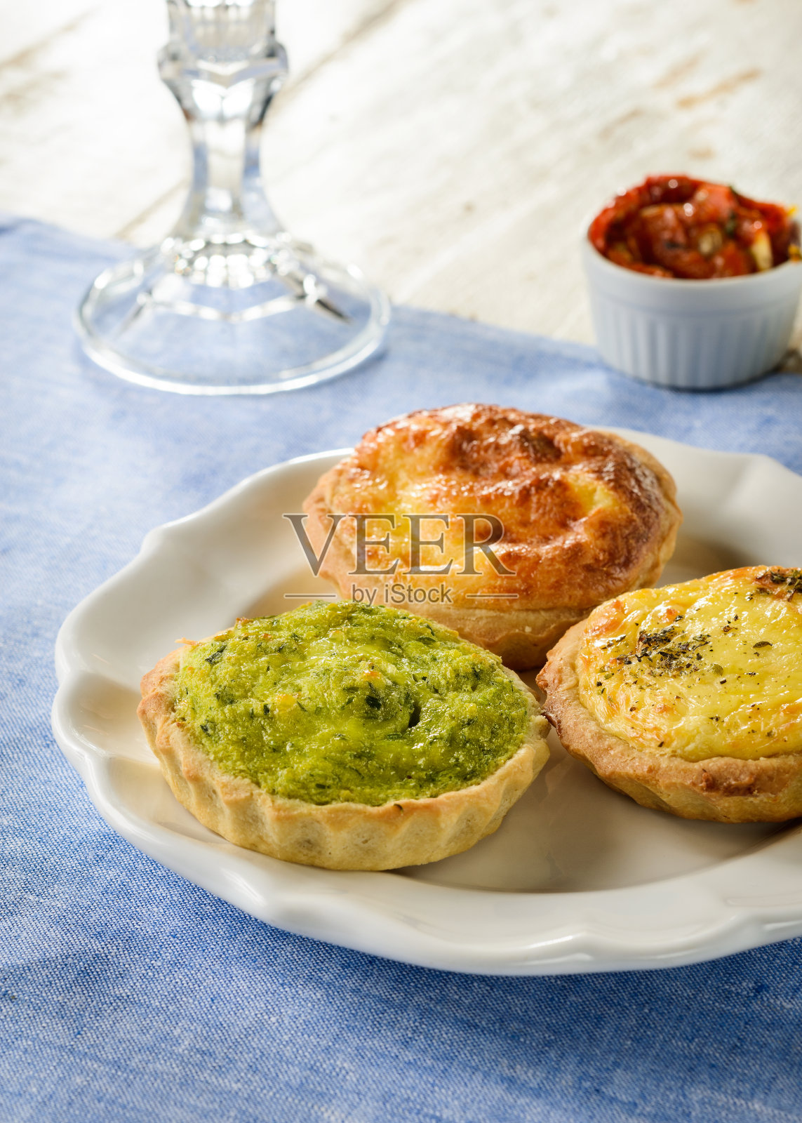 三个不同口味的美味乳蛋饼放在陶瓷盘子上，蓝色的餐垫上，木制的桌子上照片摄影图片