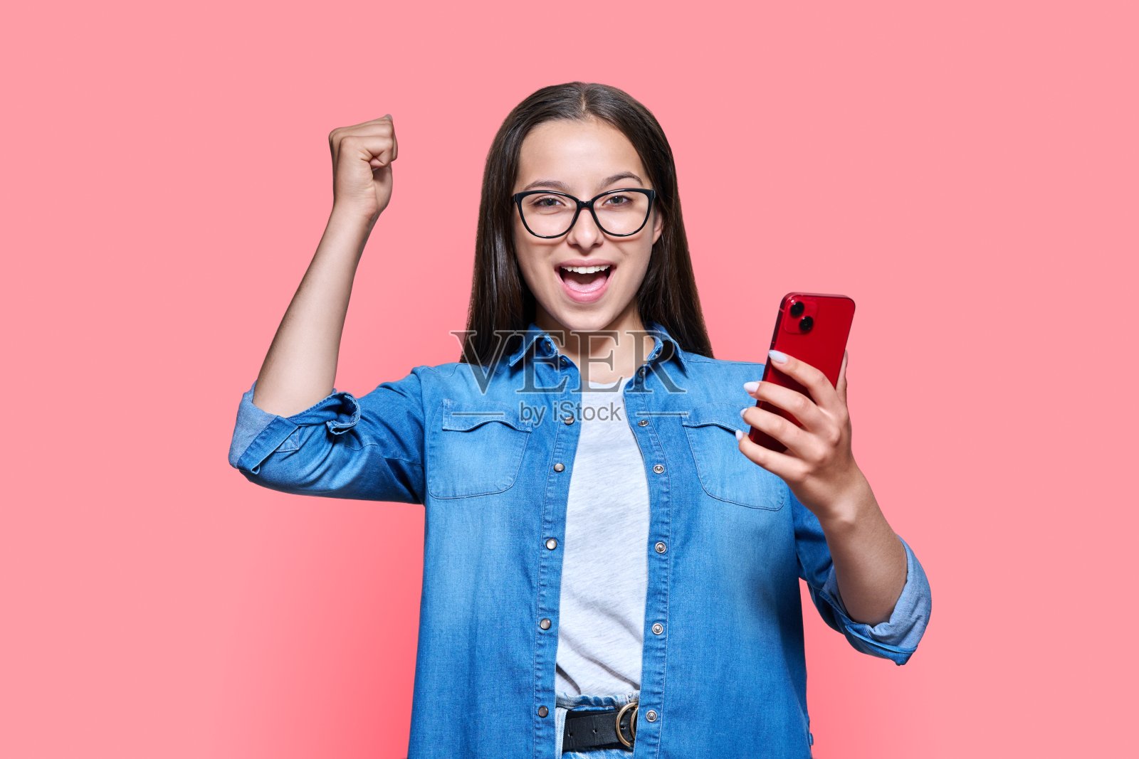 快乐的少女与智能手机，情感是成功的红粉红色的背景照片摄影图片