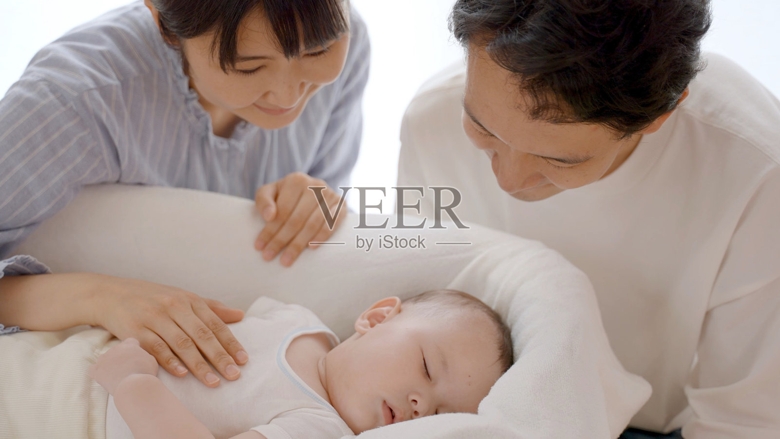 父母照看睡在床上的婴儿照片摄影图片