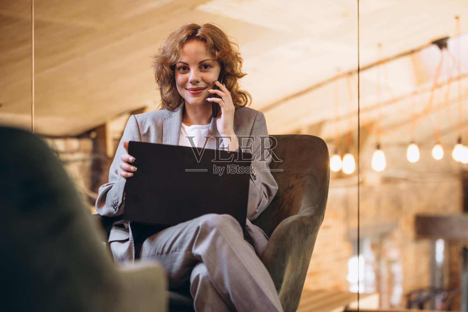 美丽的年轻自信的女人在阁楼风格的办公室与一群同事在后台。成功理念、商业、事业、成就照片摄影图片