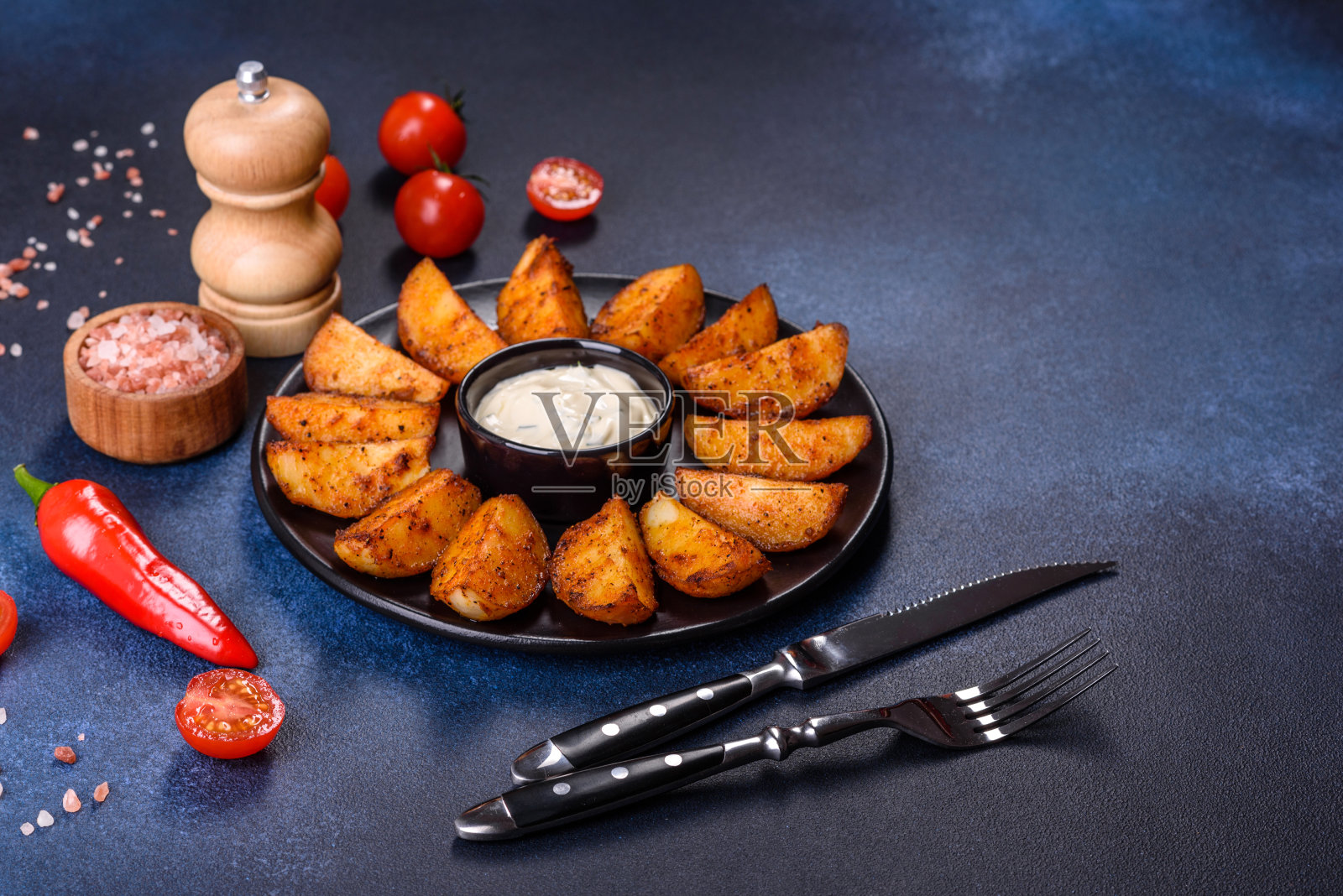 烤土豆，在黑色的背景上配上奶酪、香草和番茄酱照片摄影图片