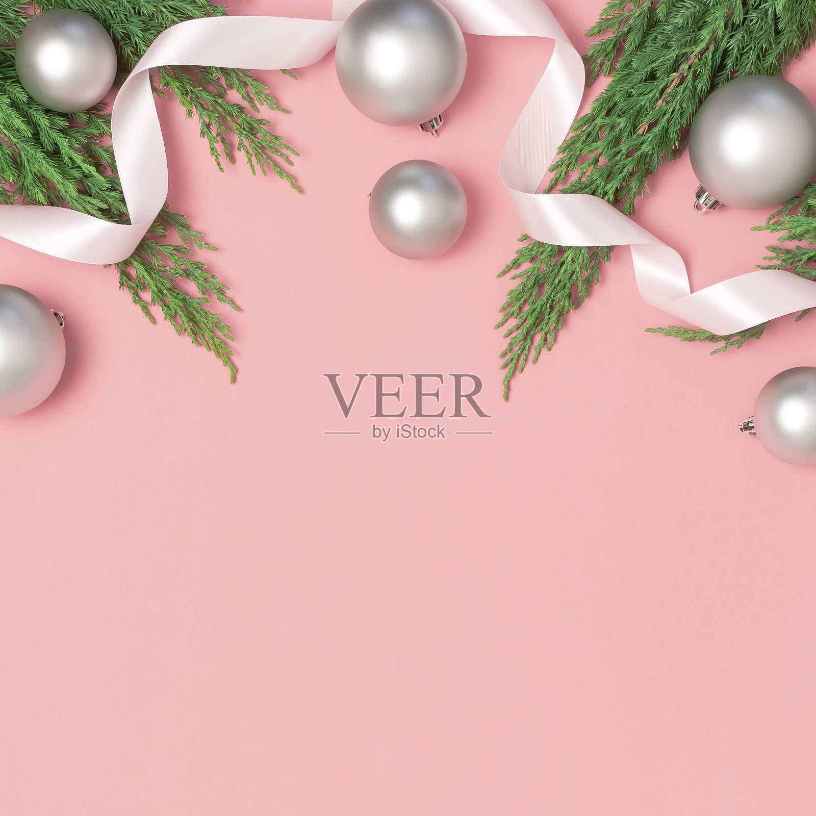 银色的圣诞玩具球，节日彩带，粉色背景的圣诞树树枝。平铺，俯视图，拷贝空间。新年的组成，冬天的装饰。最小的庆祝活动的概念照片摄影图片