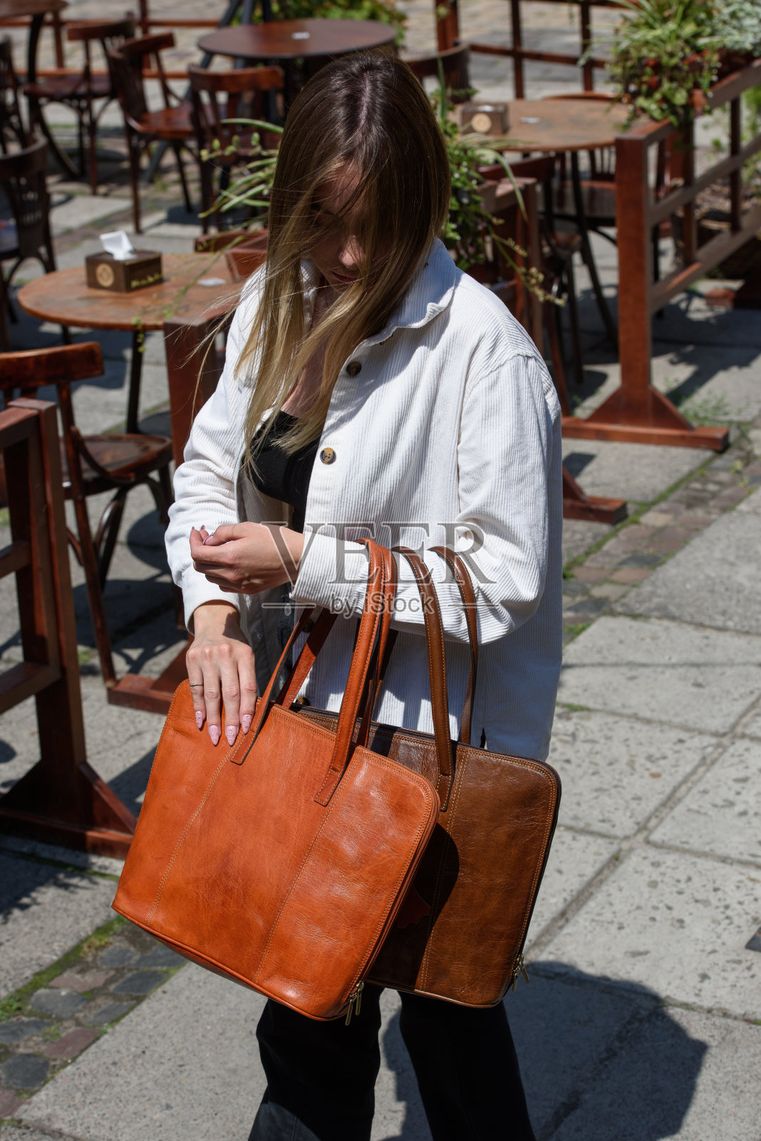 一个女人的照片与橙色和棕色的皮包。照片摄影图片