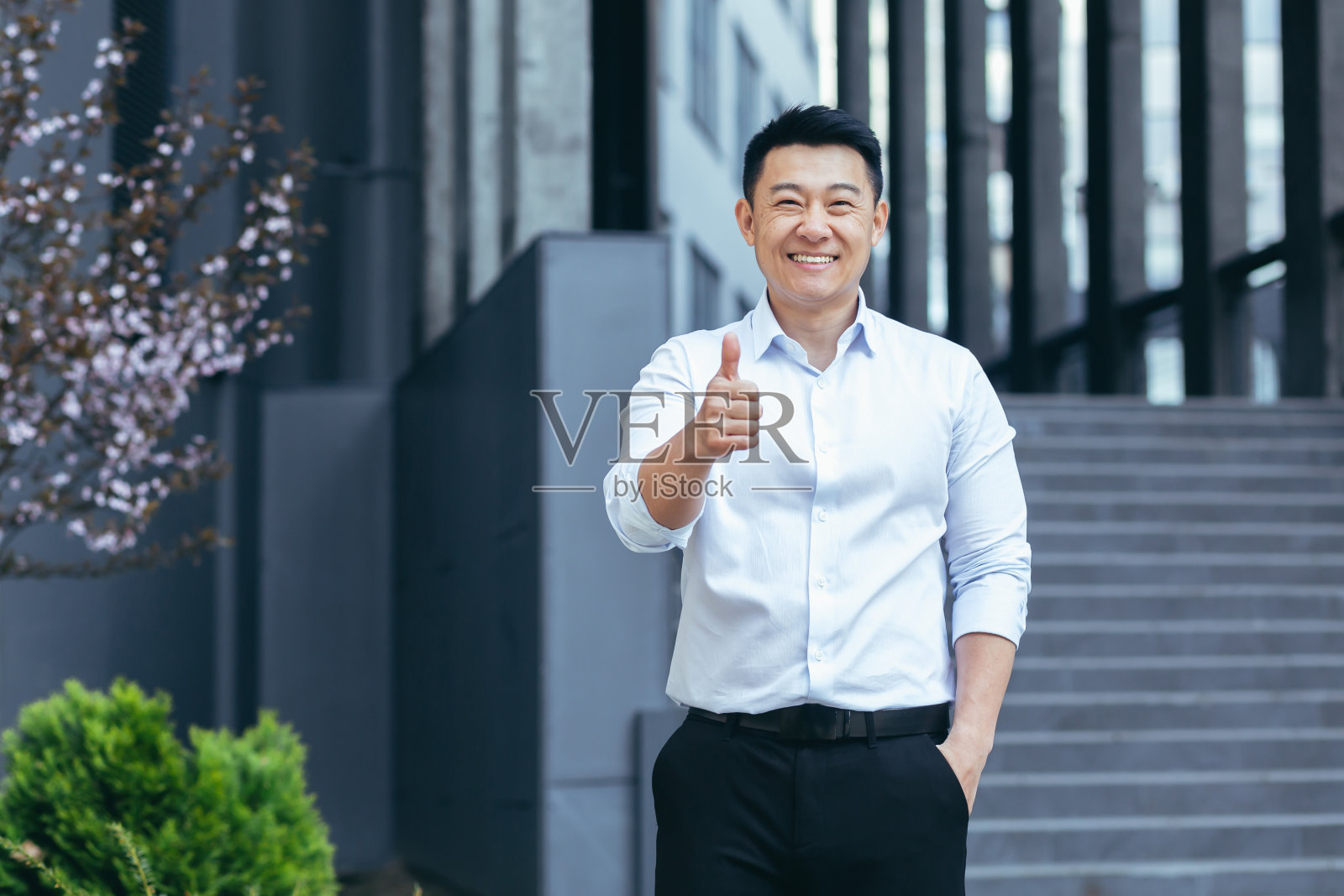 快乐的亚洲代理商人看着相机，微笑着高举大拇指在办公室外照片摄影图片