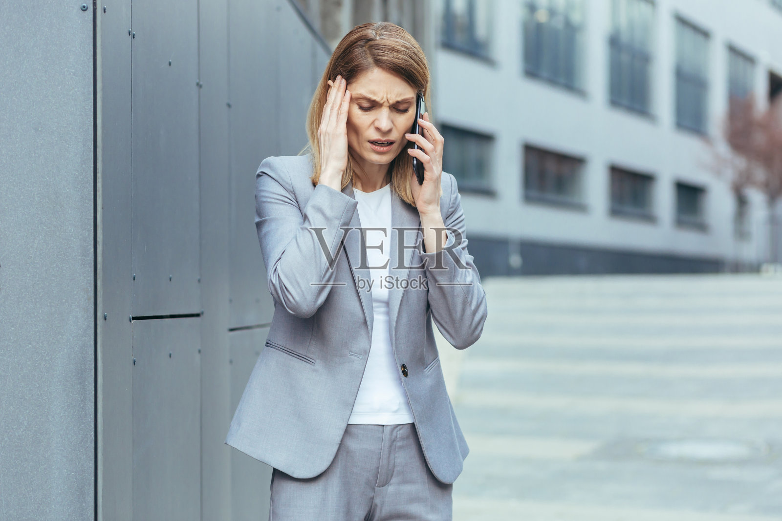 患有严重头痛的中年女商人试图打电话照片摄影图片