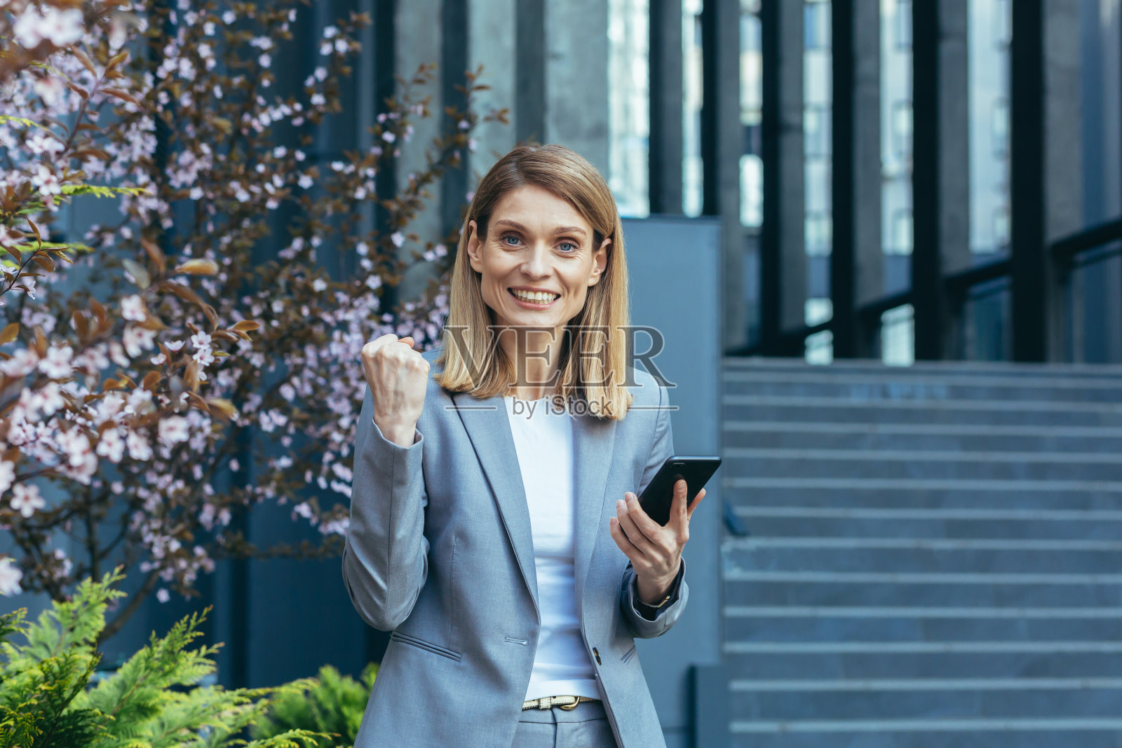 成功的商务女性在办公室外穿着商务套装读到好消息照片摄影图片