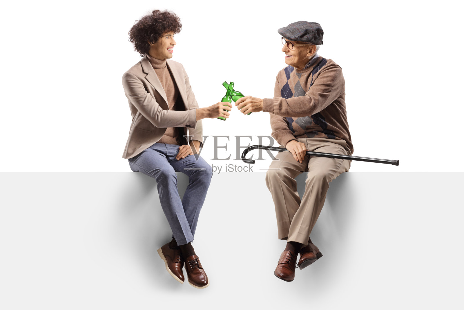 一个快乐的年轻人坐在空白的面板上，和一个老人一起拿着啤酒举杯照片摄影图片