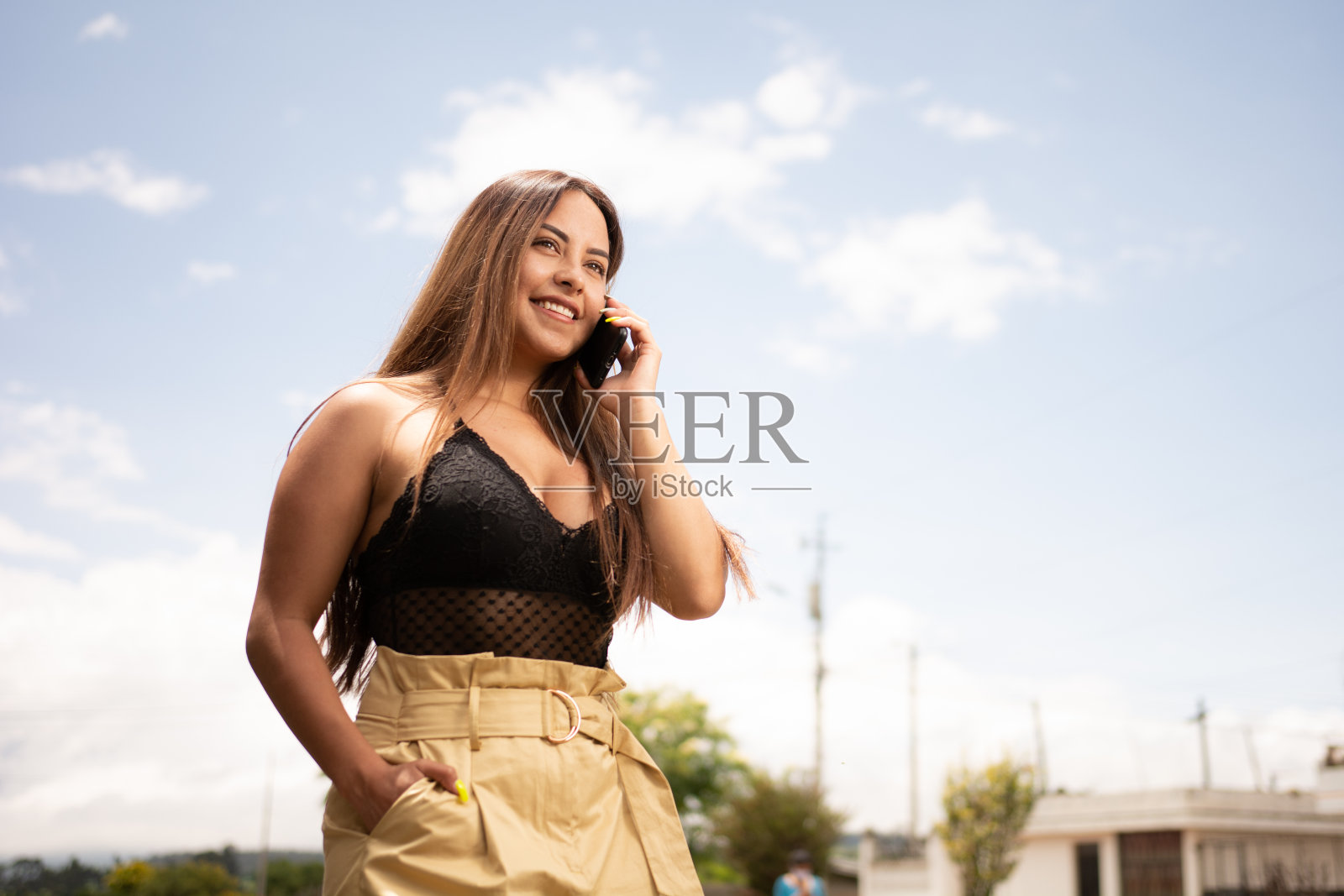 西班牙裔高管在街道上用手机微笑，背景是城市照片摄影图片