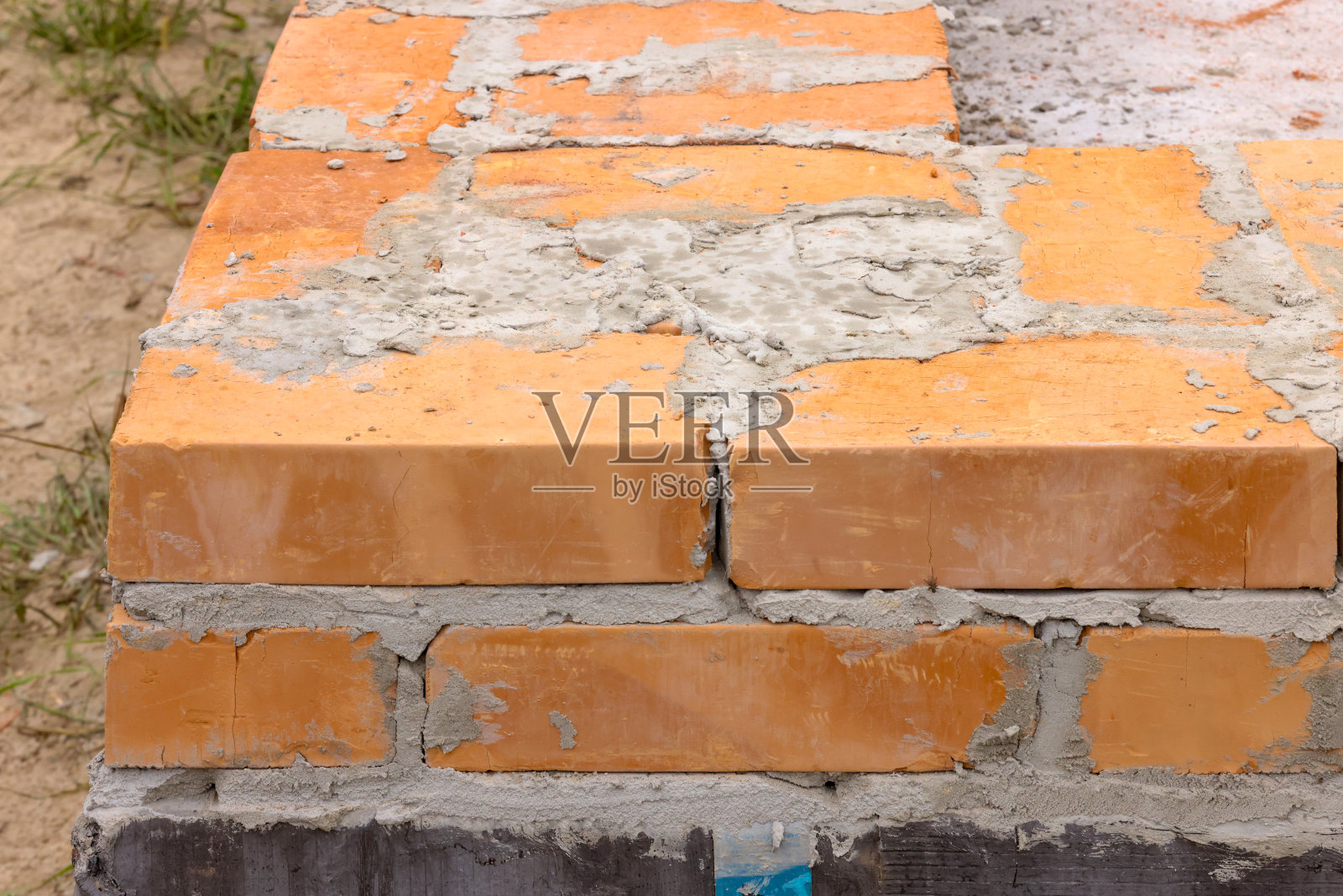 最初的几排砖瓦。建造房屋的初始阶段用橙色的陶瓷砖砌筑。照片摄影图片