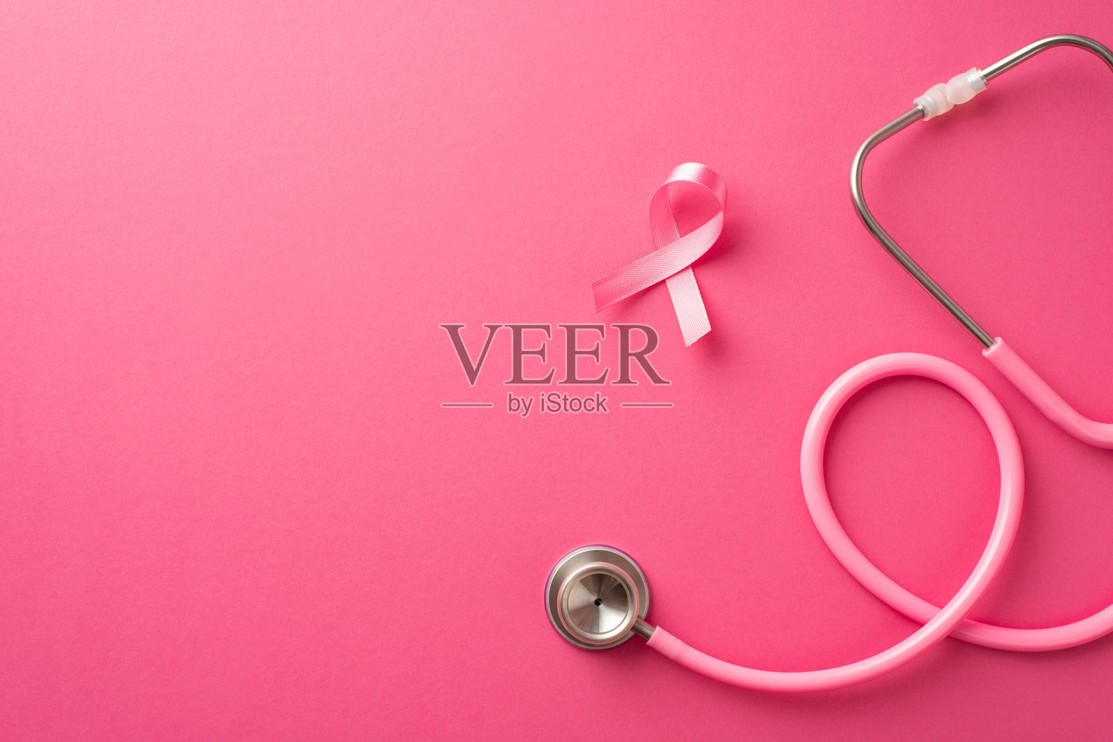乳腺癌预防概念。俯视图照片的粉红色丝带和听诊器上孤立的粉红色背景与copyspace照片摄影图片