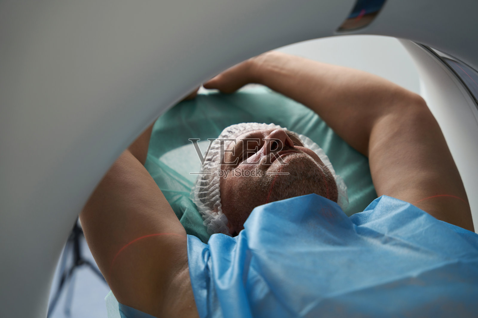 病人闭上眼睛，张开双臂躺在断层扫描室内照片摄影图片