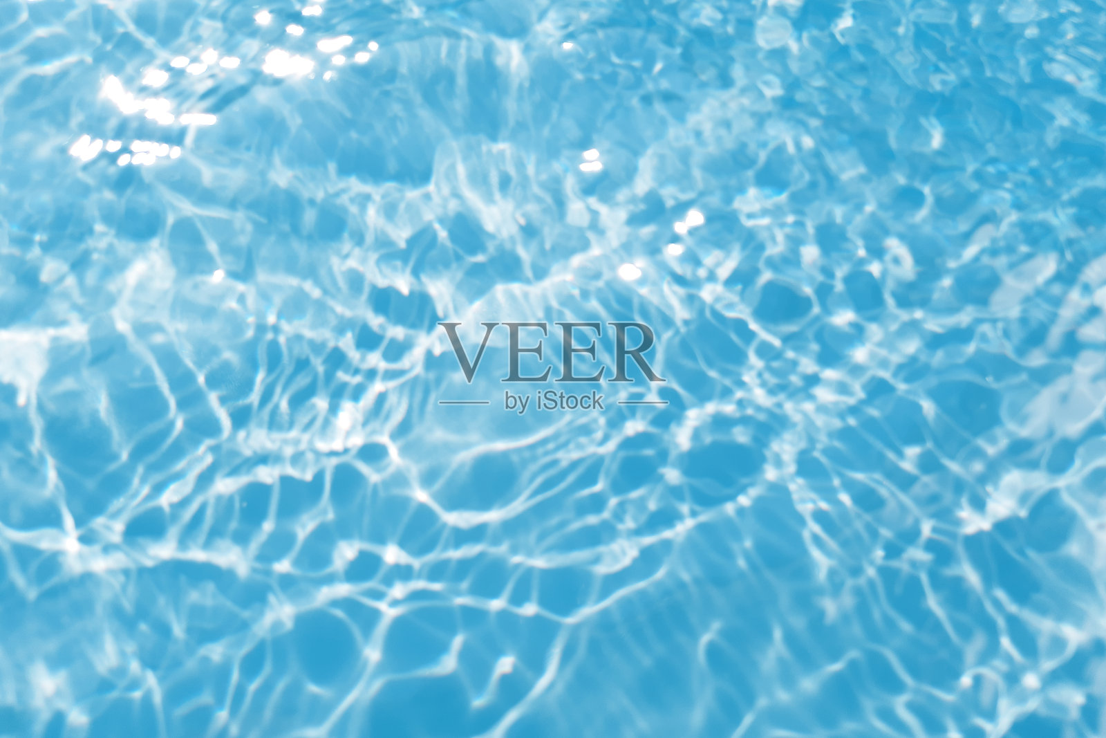 散焦模糊透明蓝色，清澈平静的水面纹理与飞溅和泡沫。时髦的抽象自然背景。阳光下的水波与复制空间。蓝色水彩纹理照片摄影图片