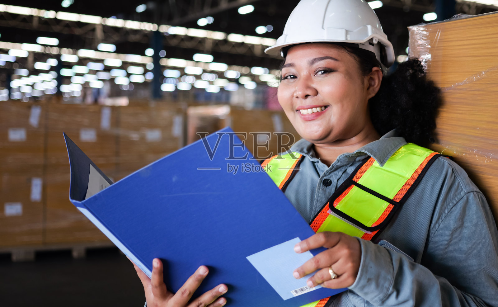 仓库工作人员戴安全帽手持文件在仓库仓库工作库存，快乐女仓库经理在工厂仓库工作，物流和业务出口的概念照片摄影图片