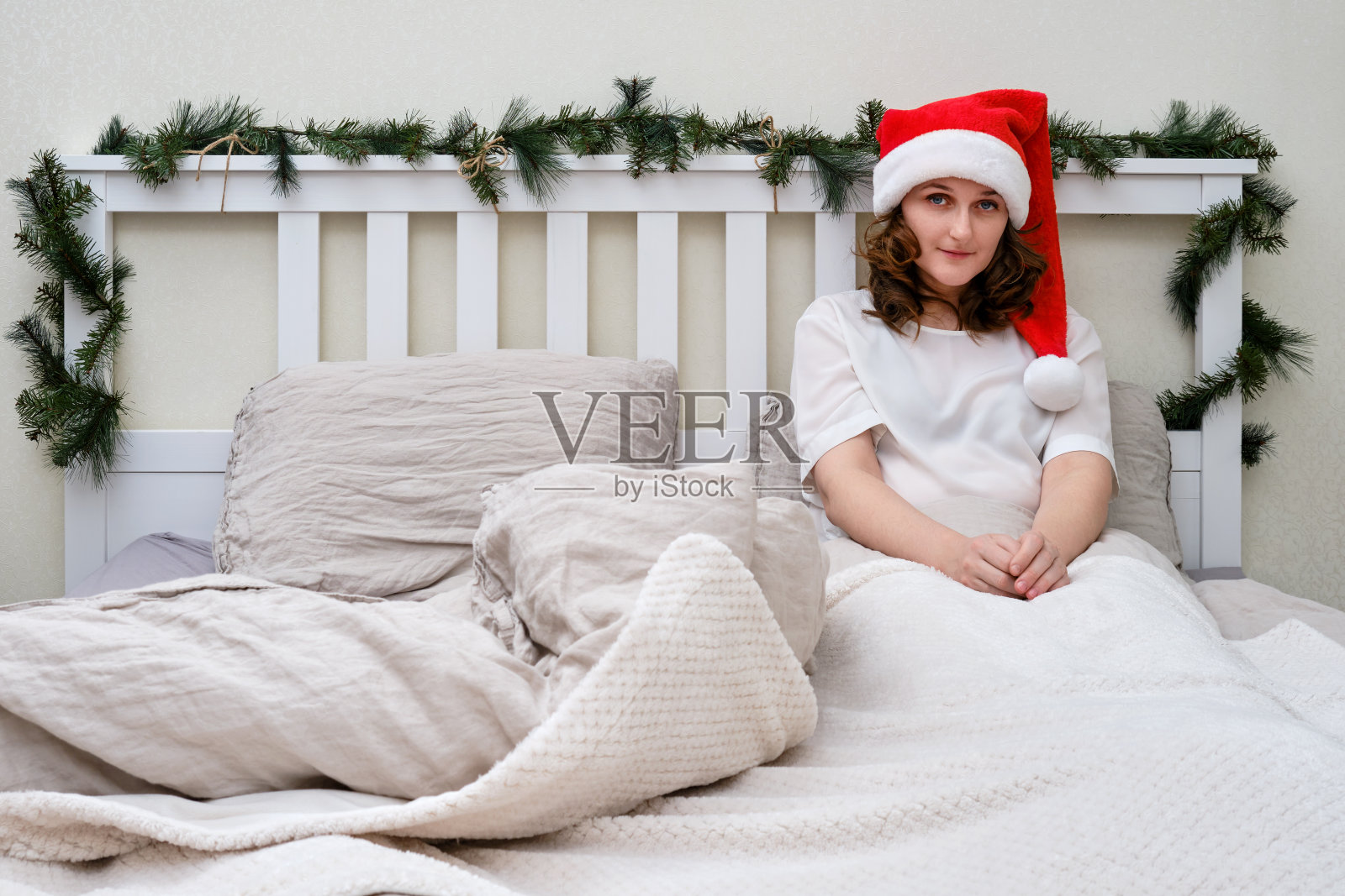 除夕，一名妇女躺在家里卧室里装饰过的圣诞床上照片摄影图片