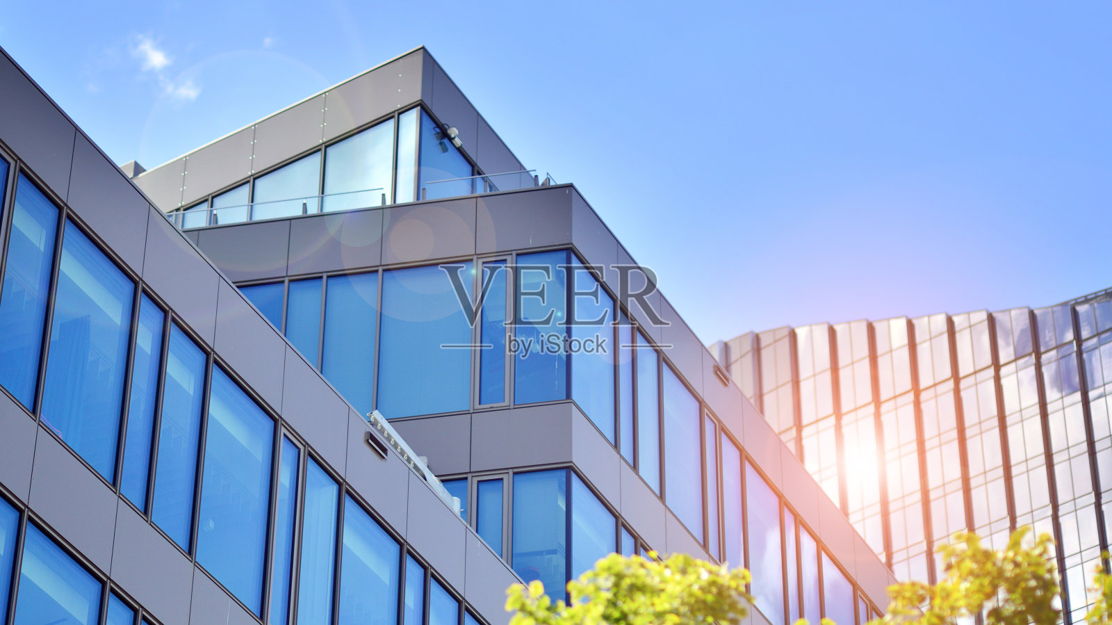 蓝色天空下的现代玻璃立面。商业区一栋建筑的底图。照片摄影图片