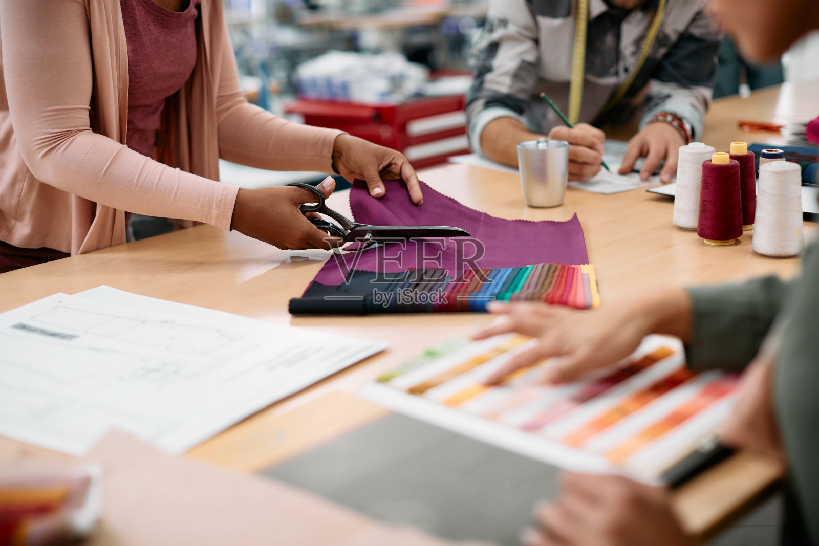 时装设计师在服装车间工作时裁剪布料的特写。照片摄影图片