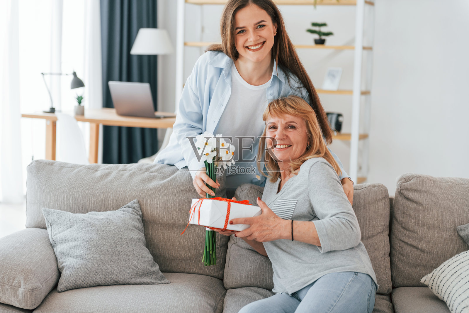 鲜花和礼物。母亲节快乐。老太太和女儿一起在家照片摄影图片