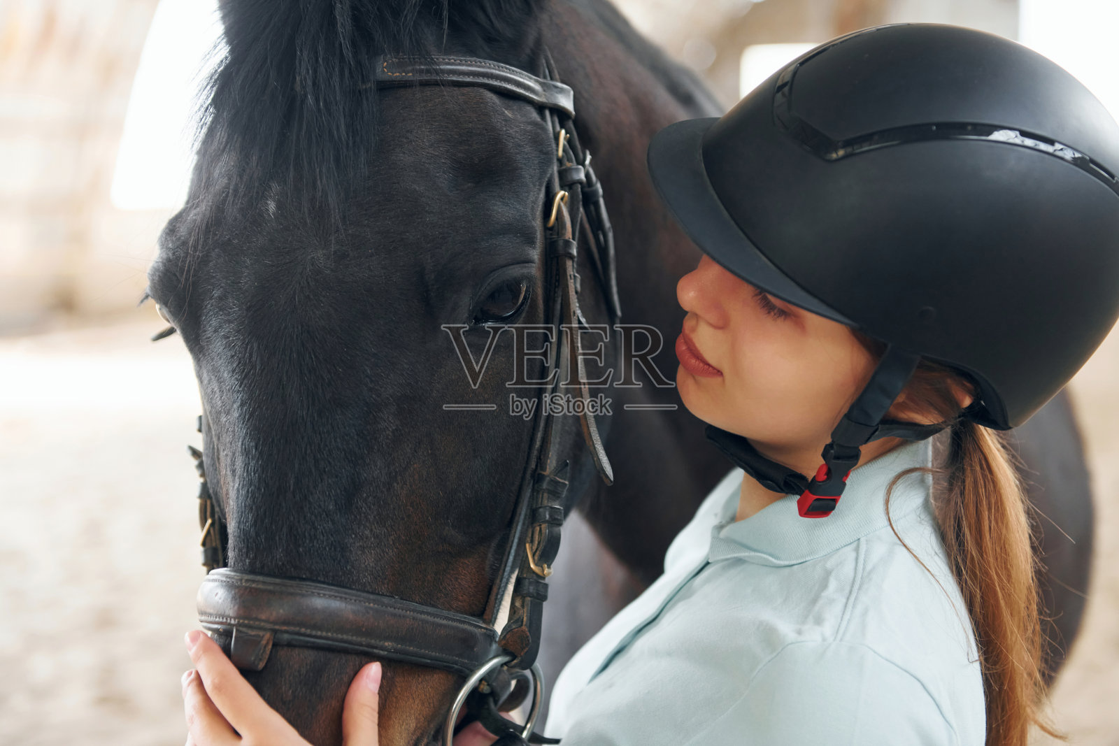关闭视图。一个穿着骑师服的年轻女子正准备在马厩里骑马照片摄影图片