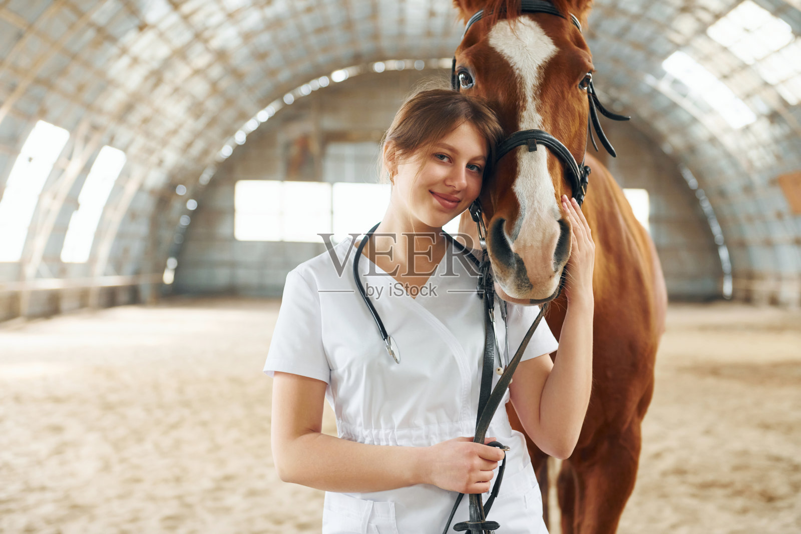 一幅穿着白大褂的女医生的画像，她和一匹马在马厩里照片摄影图片
