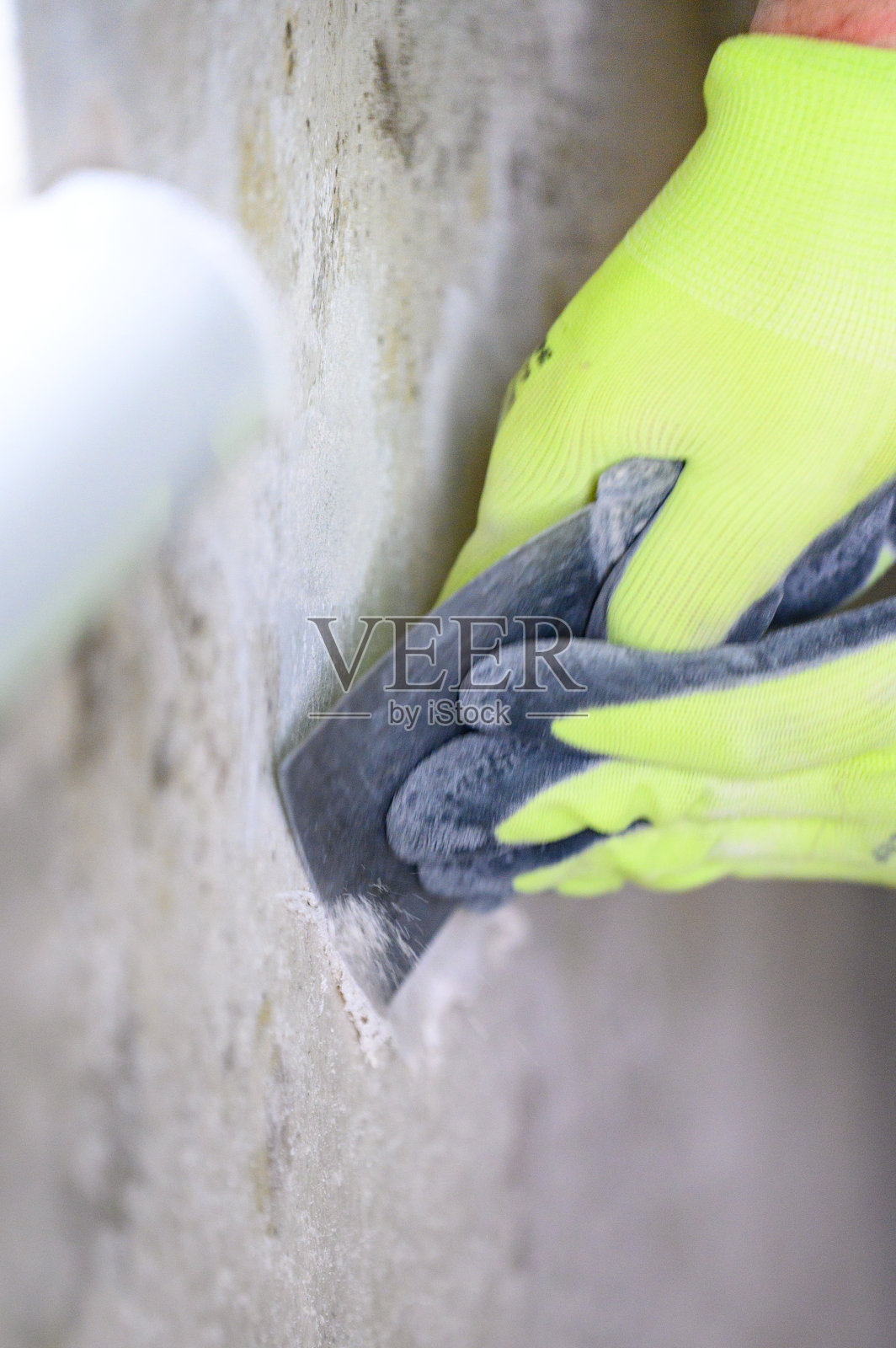 真菌和霉菌是房间里水分过多的表现，一个人用铲子从墙上清除真菌和霉菌。照片摄影图片