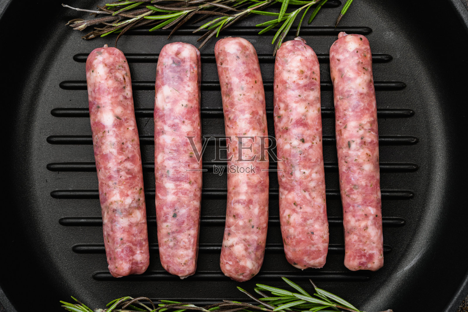 新鲜的生肉末香肠，在煎铸铁锅上，在旧的黑暗质朴的桌子背景，俯视图平躺照片摄影图片