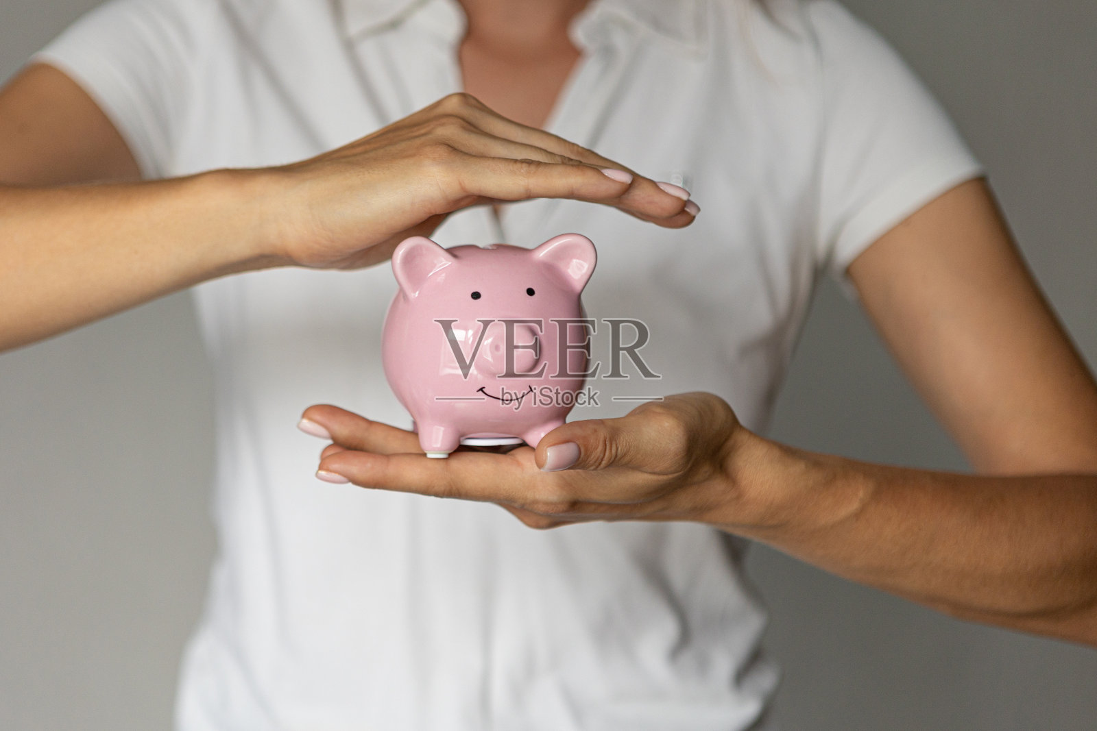室内，女人手拿粉色小猪存钱罐，投资积累危机照片摄影图片