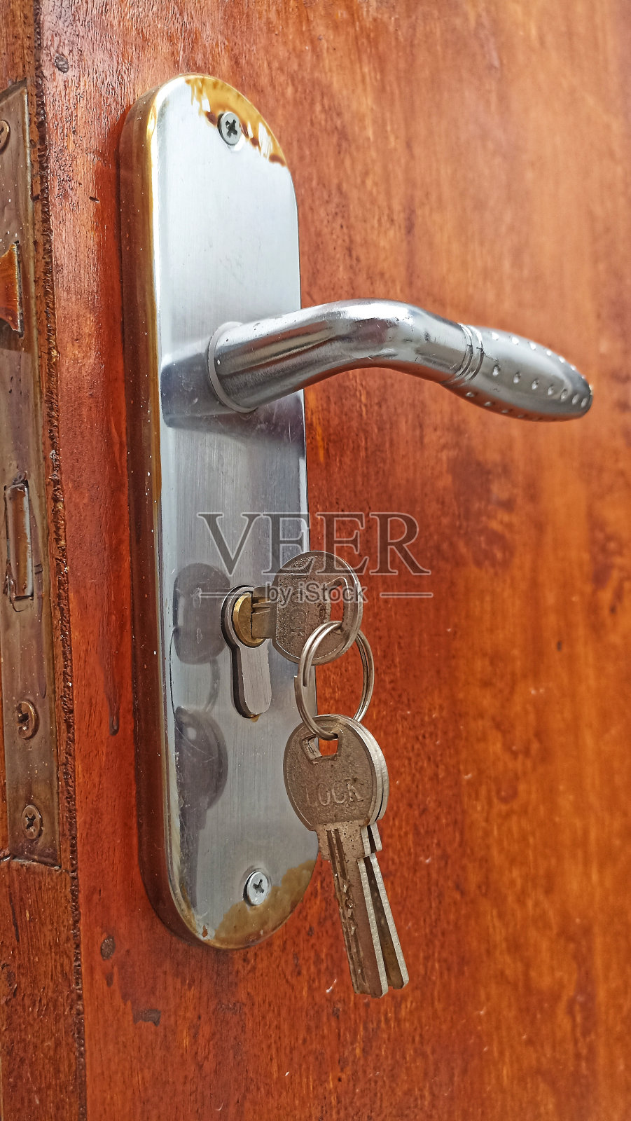 木门上的不锈钢把手，附有锁。照片摄影图片