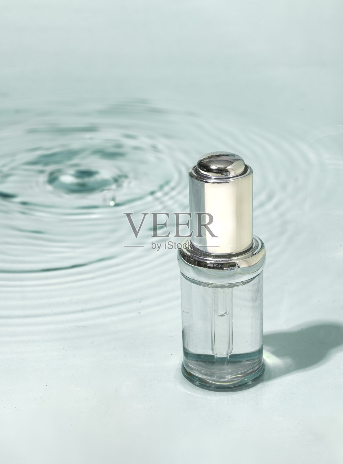 美容spa医疗护肤品，玻璃精华瓶，胶原蛋白胶束乳液，绿水背景，带波浪。白桦芽提取精华，用于抗衰老护理，保湿照片摄影图片