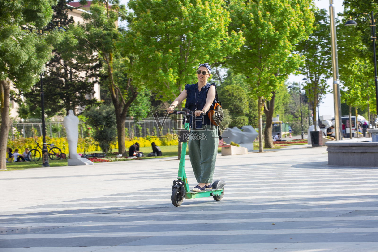 晴天时年轻女子在公园骑电动滑板车照片摄影图片