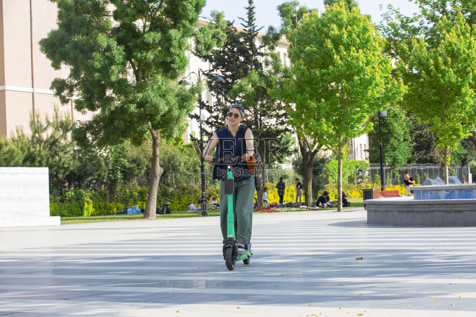 晴天时年轻女子在公园骑电动滑板车照片摄影图片