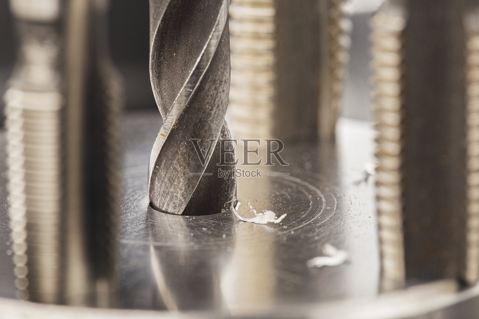 金属钻头用刨花在工业钻床上的铝坯上打孔。金属加工行业。多刀和立铣刀。照片摄影图片