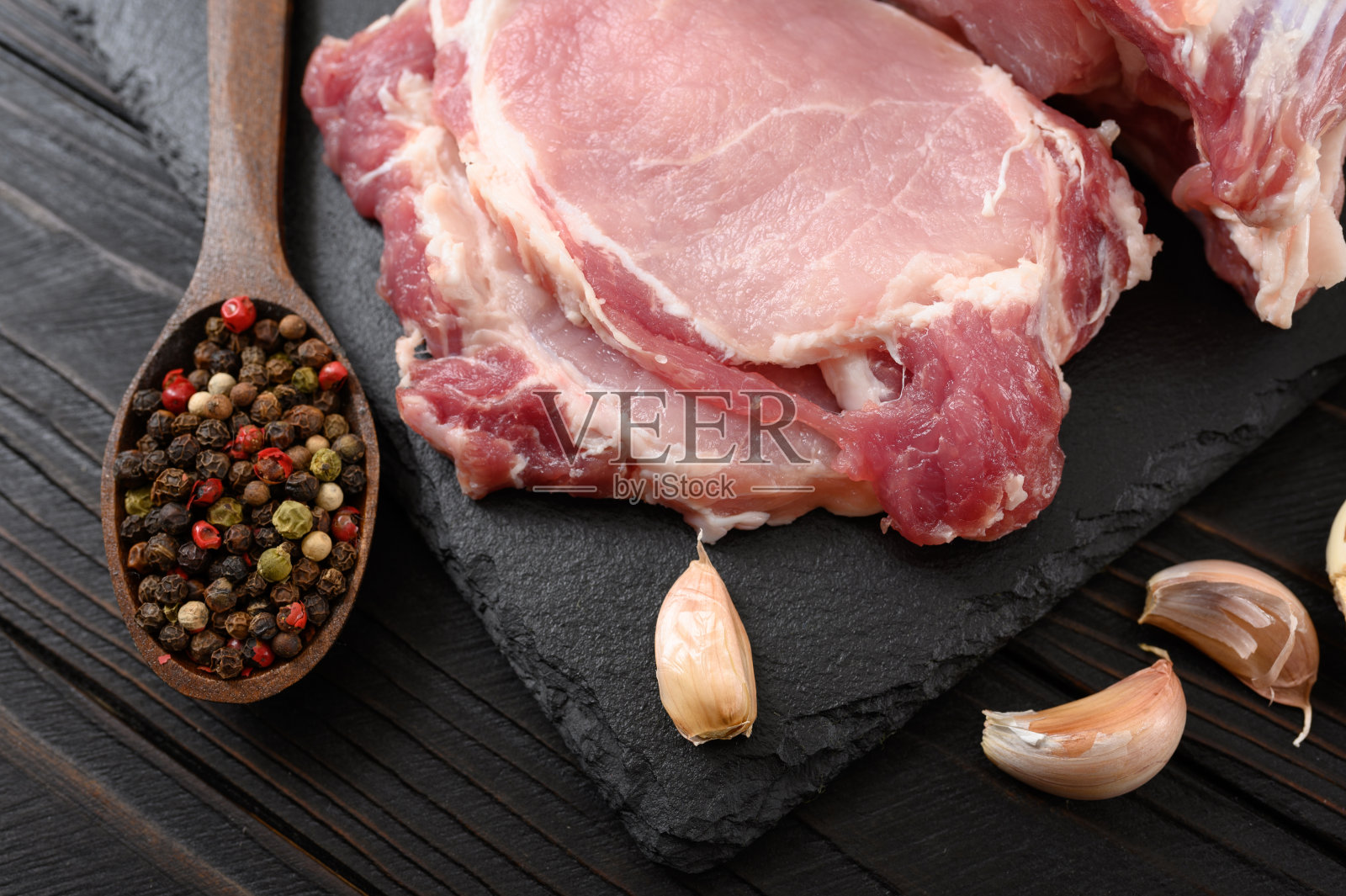 一大块猪里脊肉放在质朴的黑色背景上。照片摄影图片