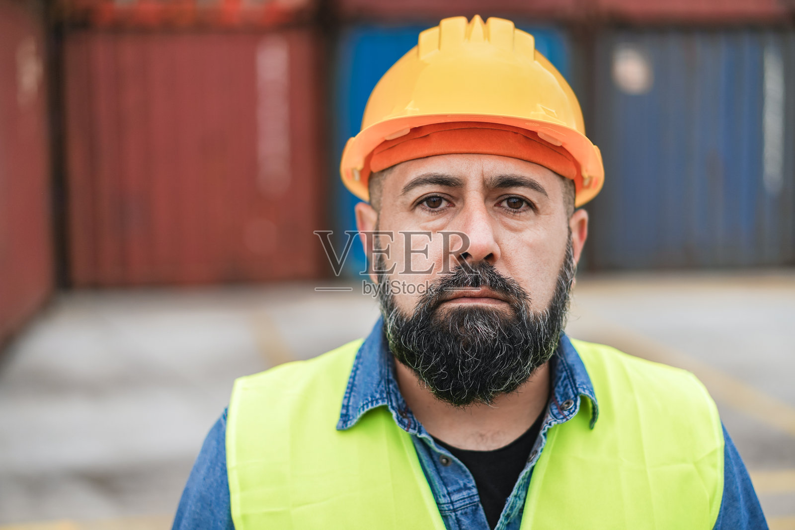 拉丁工人中年男子看相机与工业港口的背景-集中在嘴照片摄影图片