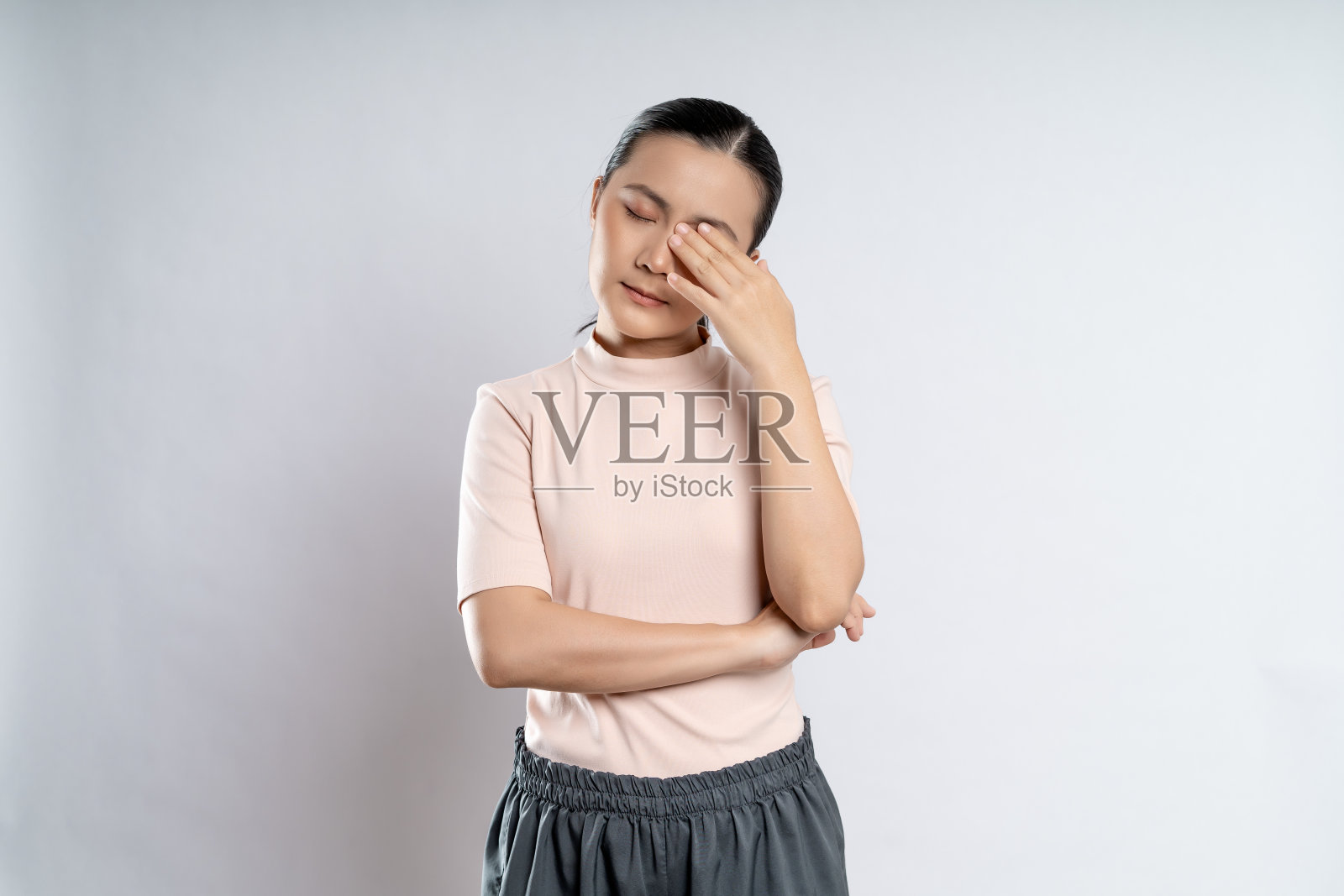 一名亚洲妇女因眼睛疼痛而生病，孤立地站在白色背景上。照片摄影图片