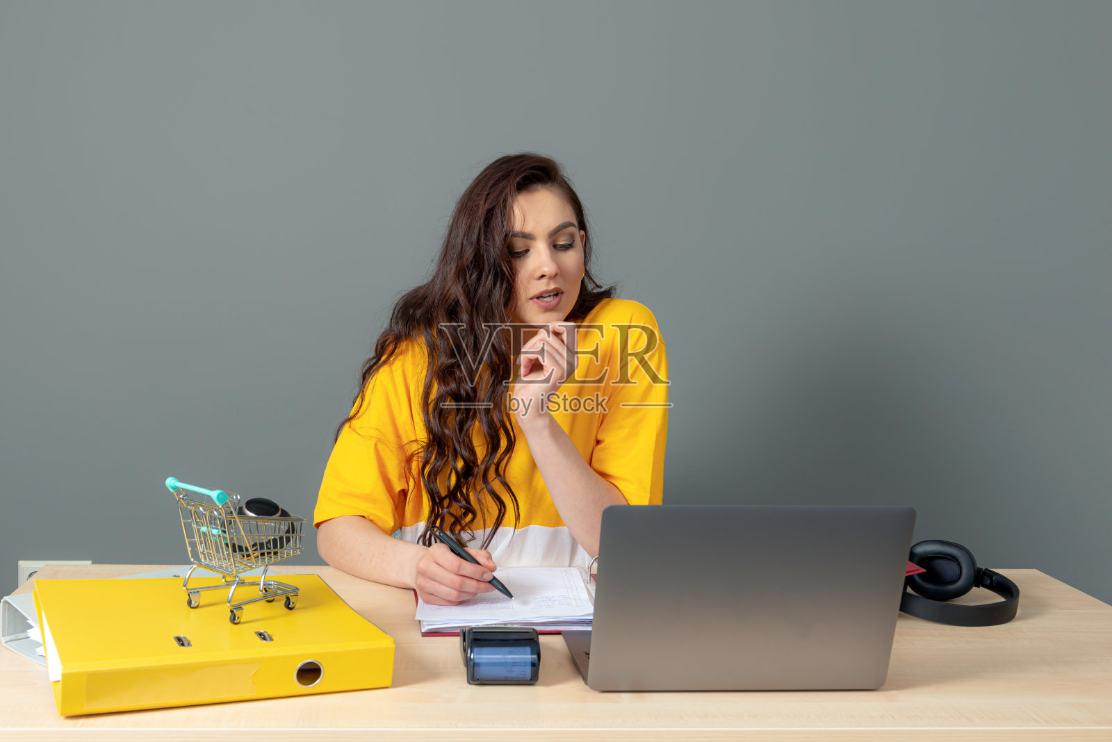 这位年轻的网店经理坐在办公室的办公桌前，用笔记本电脑和文件工作照片摄影图片