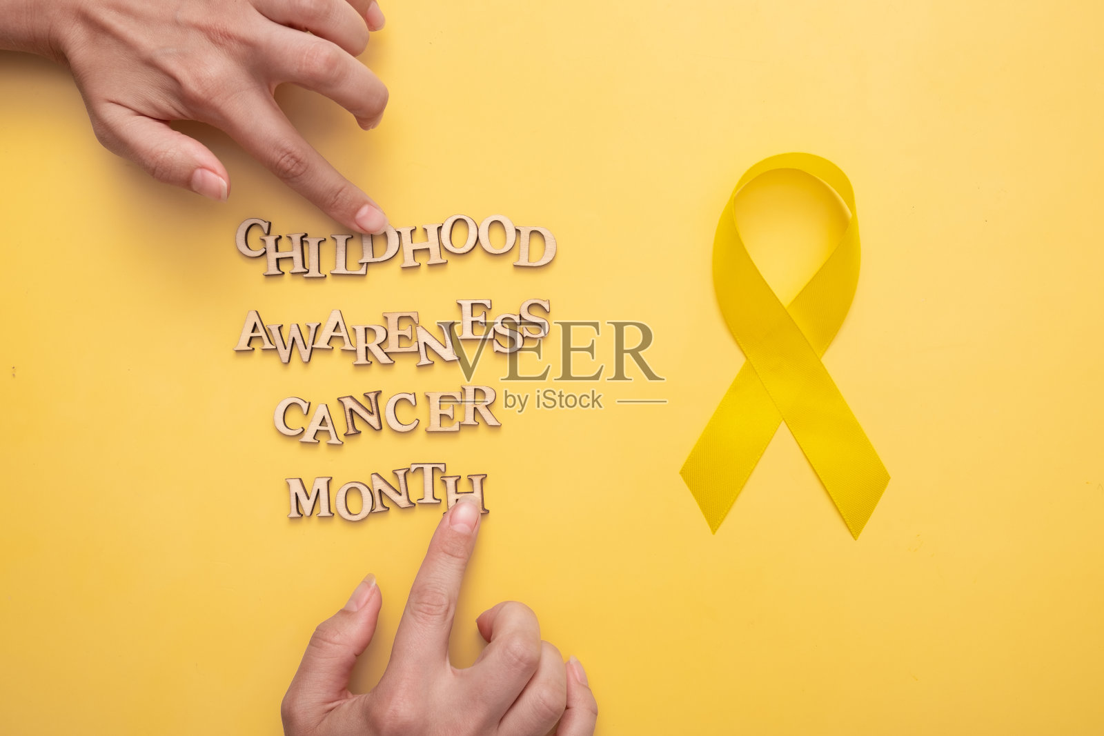 木制字母、女性手部和黄色丝带，关注儿童癌症宣传月照片摄影图片