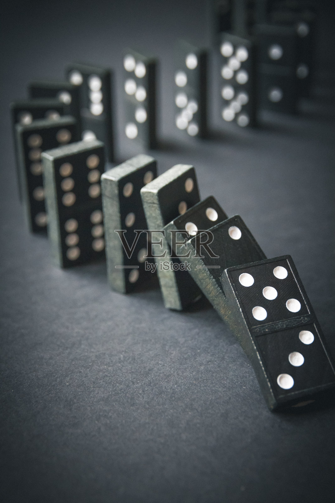 黑色多米诺骨牌链在黑暗的桌子背景照片摄影图片