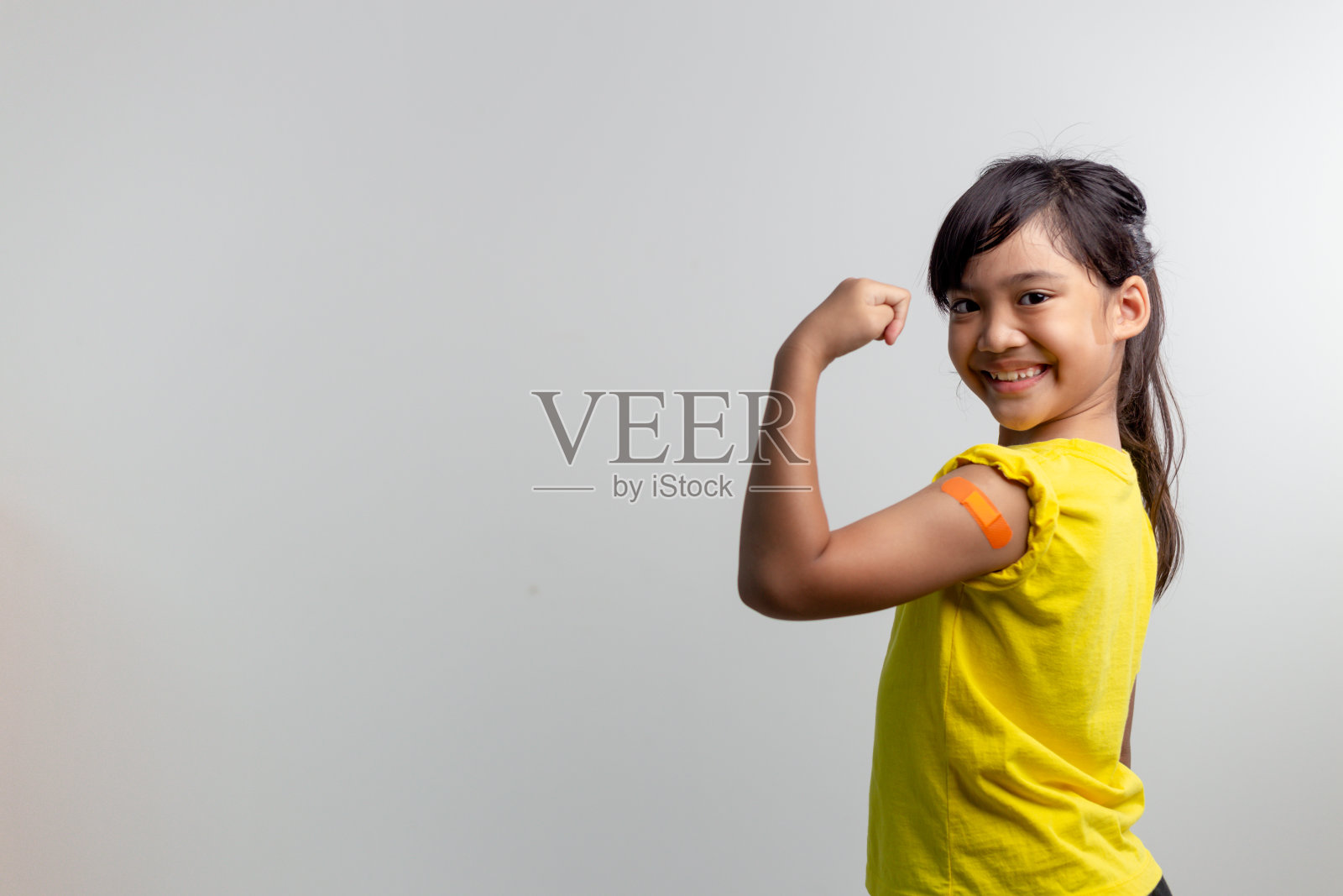 COVID 19儿童疫苗概念。工作室拍摄了一个可爱的亚洲女孩在接种第一剂疫苗后的肖像。免疫，安全，可用，回到学校。照片摄影图片