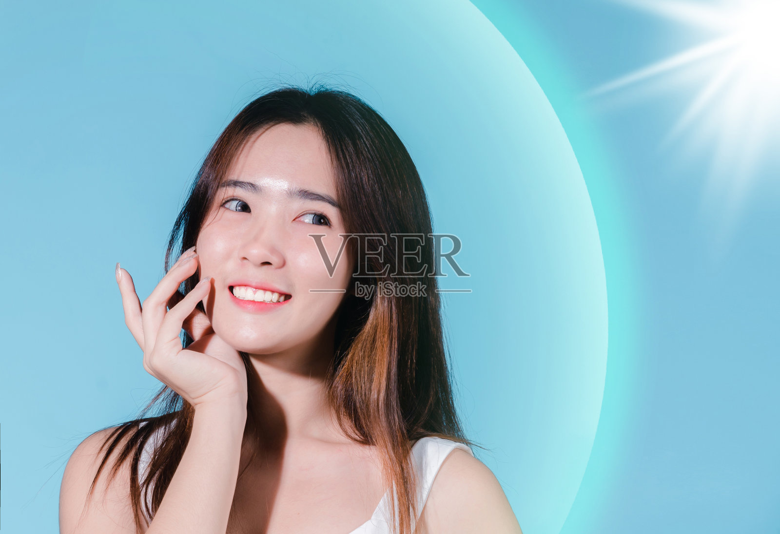 微笑的亚洲美女持有防晒霜与防晒紫外线或防晒霜，防晒霜在蓝色的背景照片摄影图片