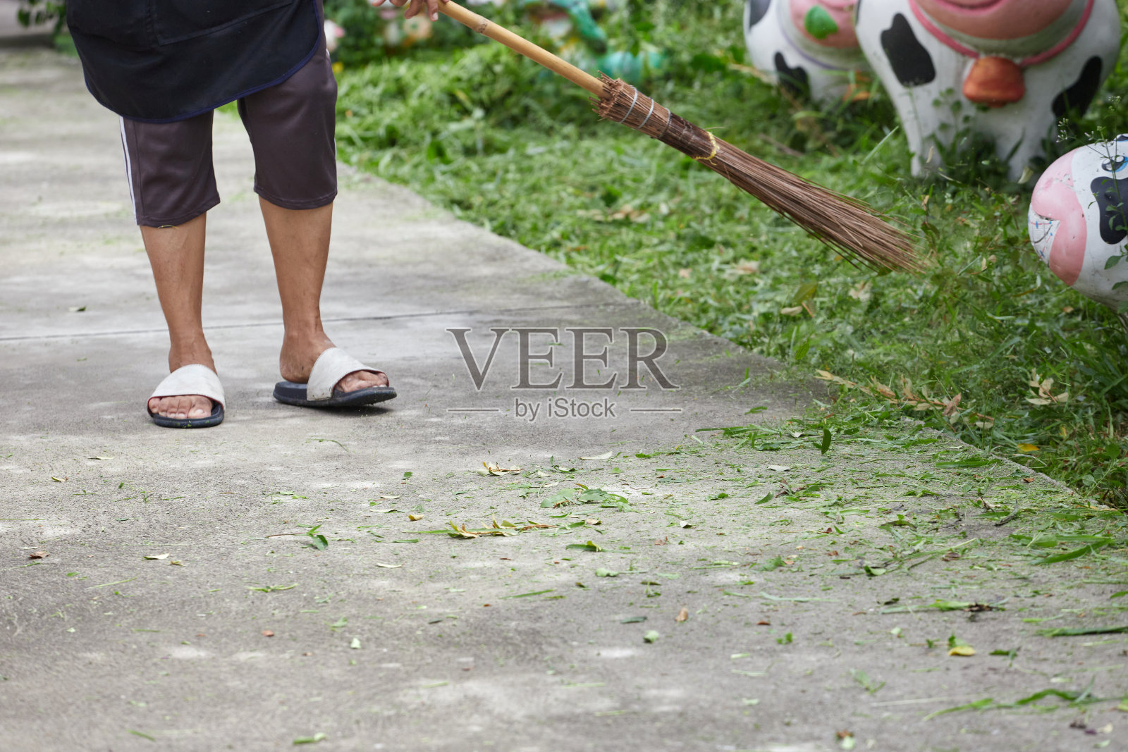 一位妇女修剪完草坪后扫地照片摄影图片